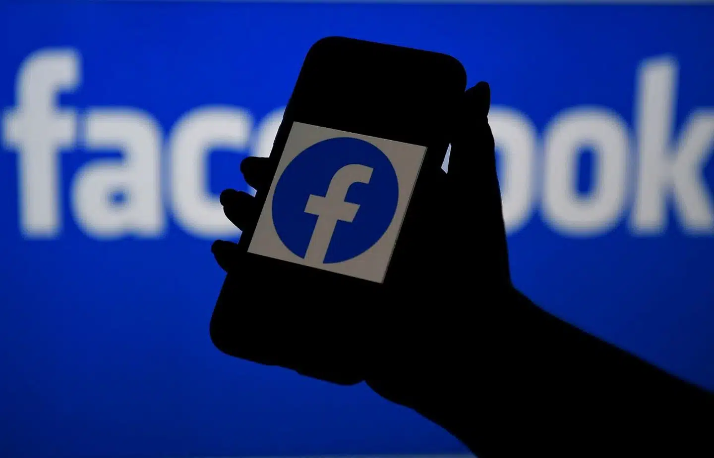 (FILES) In this file photo illustration taken on April 7, 2021, a smart phone screen displays the logo of Facebook on a Facebook website background, in Arlington, Virginia. - Facebook said March 10, 2022 that due to the invasion of Ukraine it has temporarily eased its rules regarding violent speech to allow statements like "death to Russian invaders, " but not credible threats against civilians. (Photo by OLIVIER DOULIERY / AFP)