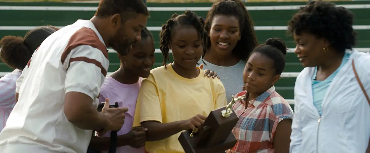 Venus Williams (spillet af Saniyya Sidney) modtager en pokal, og hele familien smiler. Også den yngre søster, Serena, der ikke får en træner, men må lære tennis af sin mor. At den bagside er udeladt, siger en del om »King Richard«.