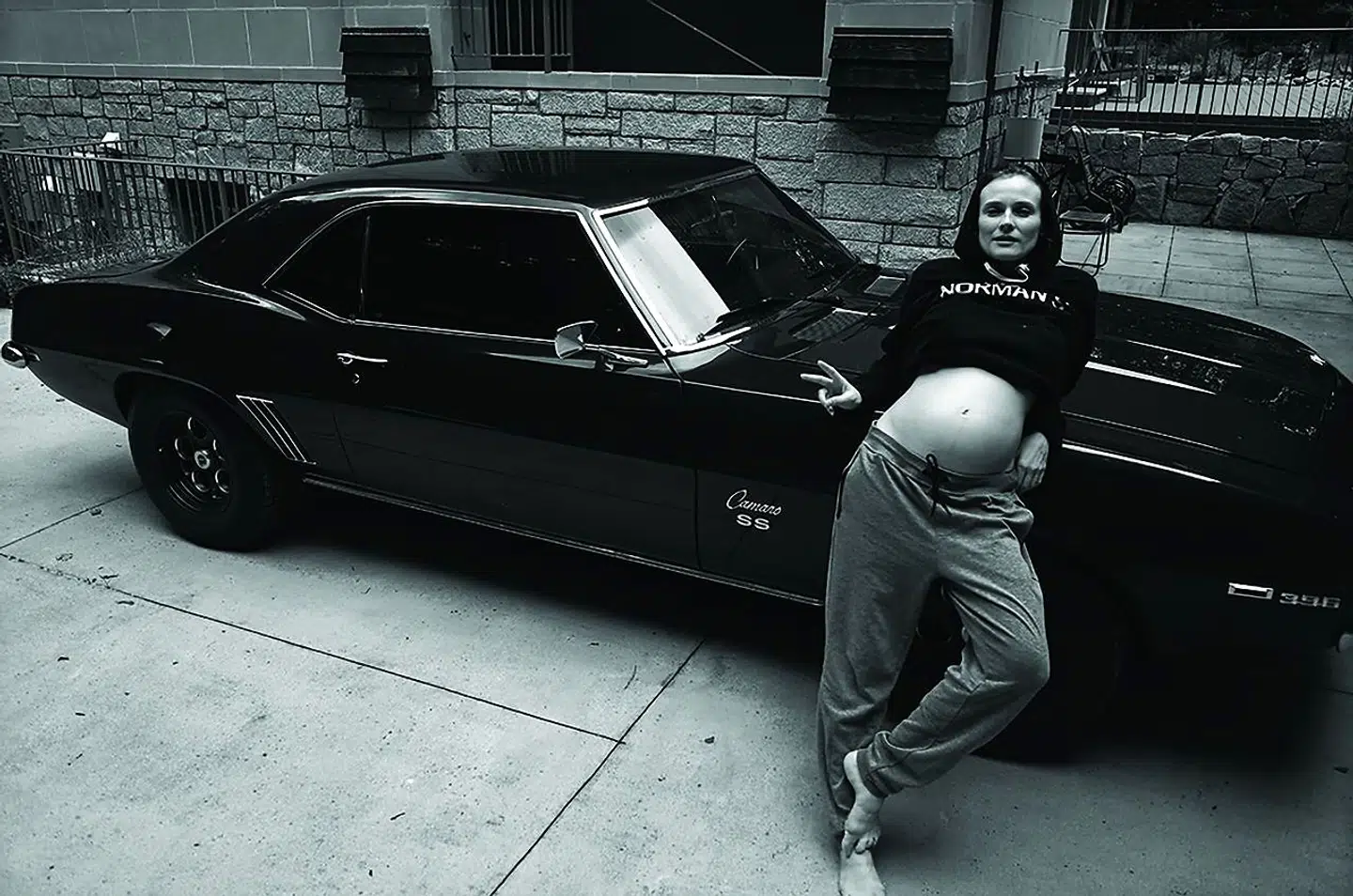 Norman Reedus autobiografiske materiale bevæger sig konstant på kanten mellem fiktion og virkelighed, som her, hvor hans kone, skuespilleren Diane Kruger, poserer med bar gravid mave og peace-tegn op ad en laksort Camaro-køler. Norman Reedus: »Ride or Die«, 2018.