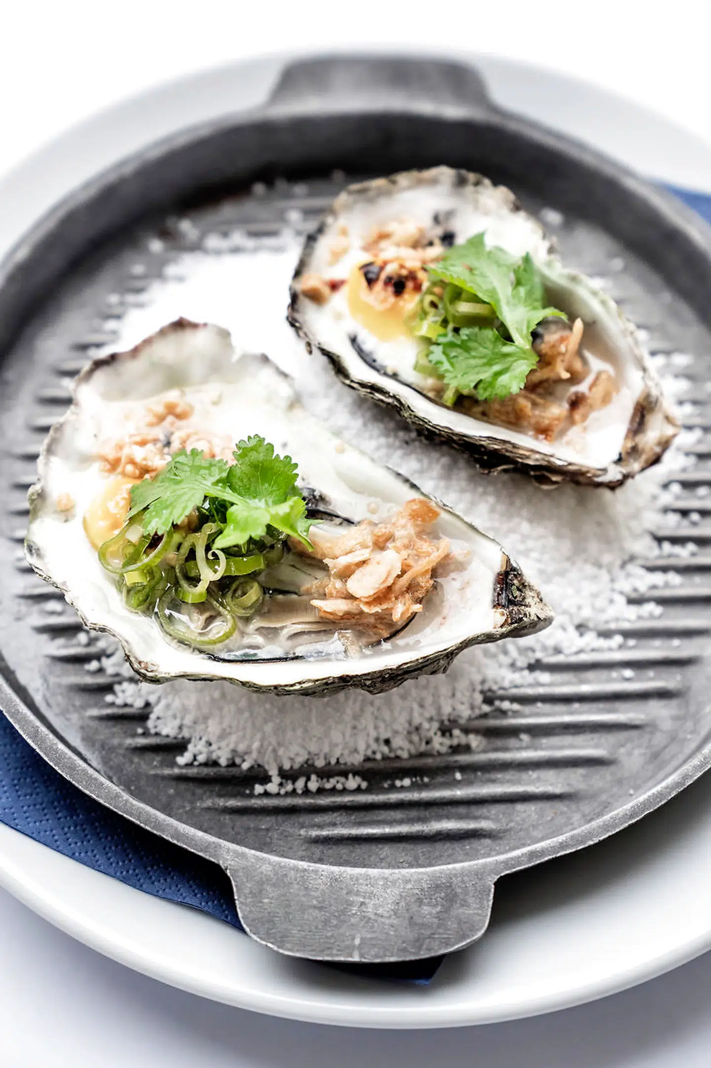 Grillede østers med vagtelæg og forårsløgsolie.