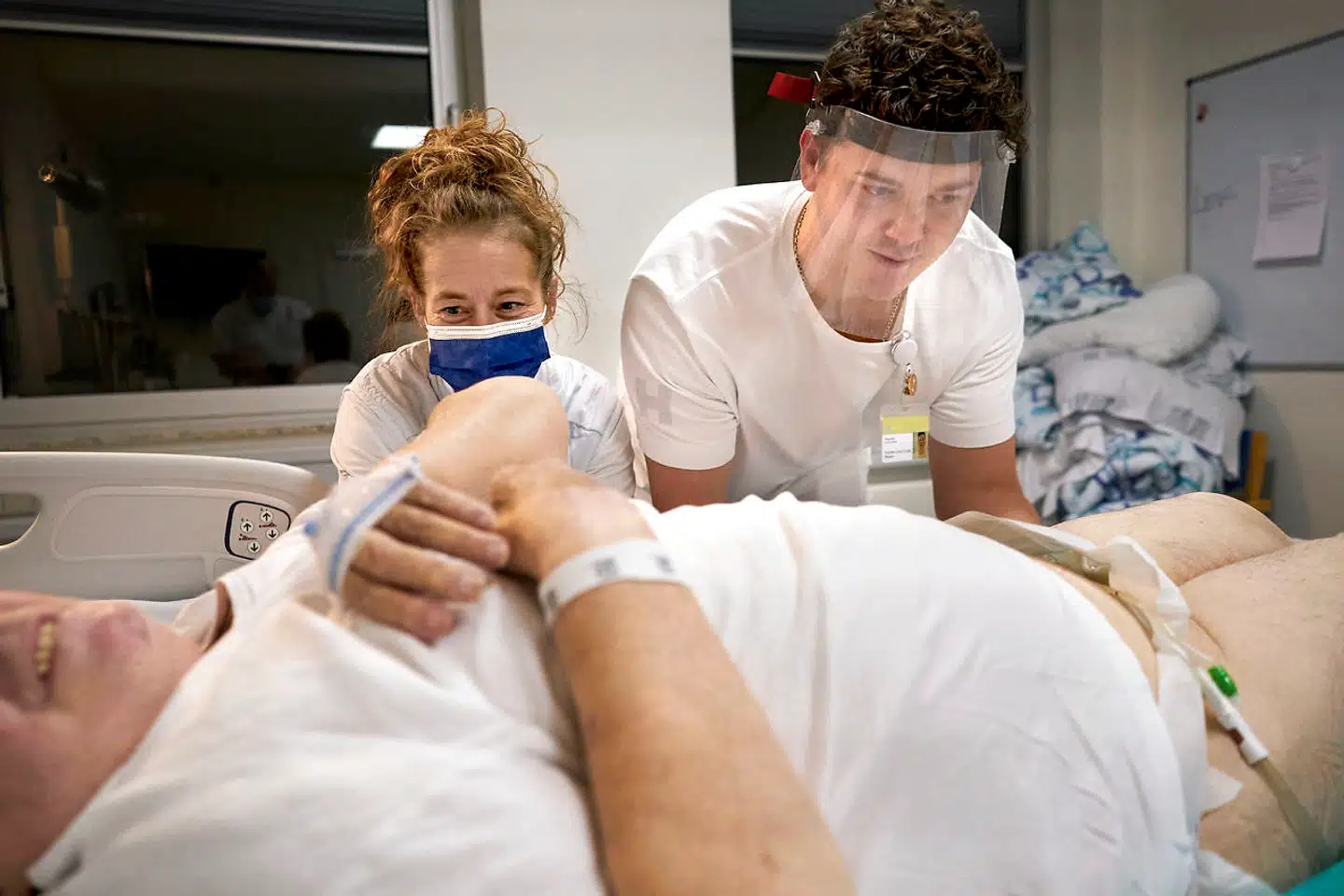 60 'plejeportører' på Glostrup Hospital har ved siden af deres normale opgaver med at transportere patienterne rundt også vagter, hvor de er med til at pleje og passe patienterne. Hér er portør Raphael Nielsen sammen med en sygeplejerske ved at lejre en patient ordentligt i sengen.