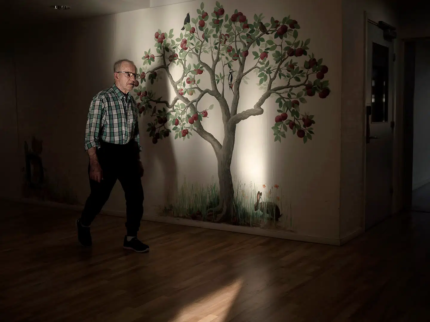 78-årige Benny vandrer ofte op og ned ad gangene på plejehjemmet Ålholmhjemmet. Væggene er udsmykket med malerier, der spreder farve og gør det nemmere for de demente beboere at finde rundt.