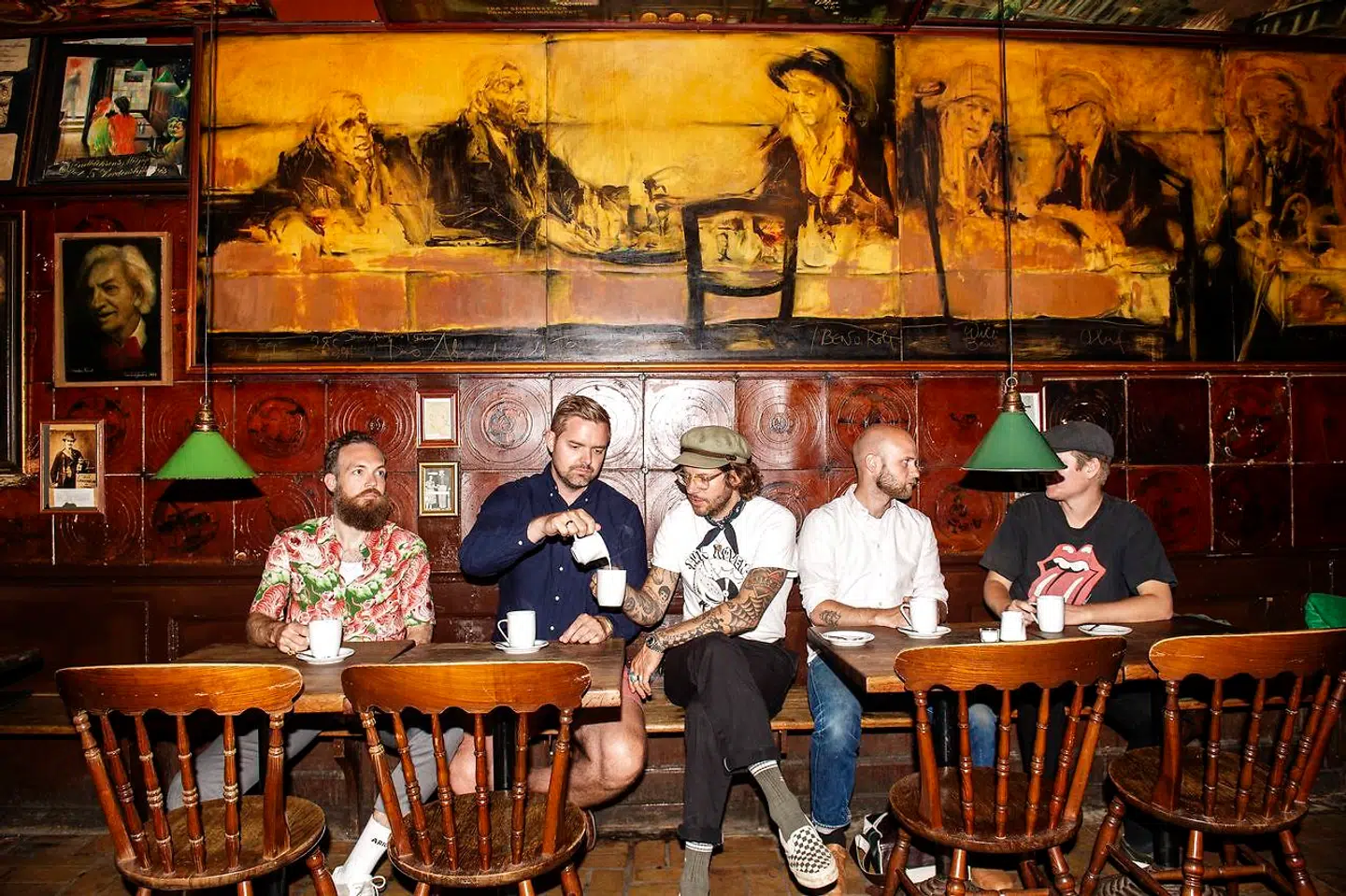 Holdet bag Stamsteder består af Anders Højberg Kamp (th) og Johannes Jacobsen (forfatterne), Thomas Skou (fotograf) i midten, mens Peter Buch Hansen og Kasper Bjerre (tv) er ophavsmænd til ideen og redaktører på bogen. Her på Skindbuksen i Indre By under et maleri af mere eller mindre prominente stamgæster gennem tiden - blandt andre forfatteren Jens August Schade.