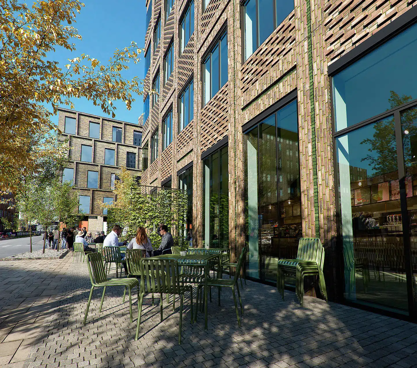 Facaden er åben ud mod gaden og skal rumme butikker og en restaurant. Med relieffer i den røde teglfacade vil arkitekterne skabe balance mellem den nye karré og de historiske omgivelser.