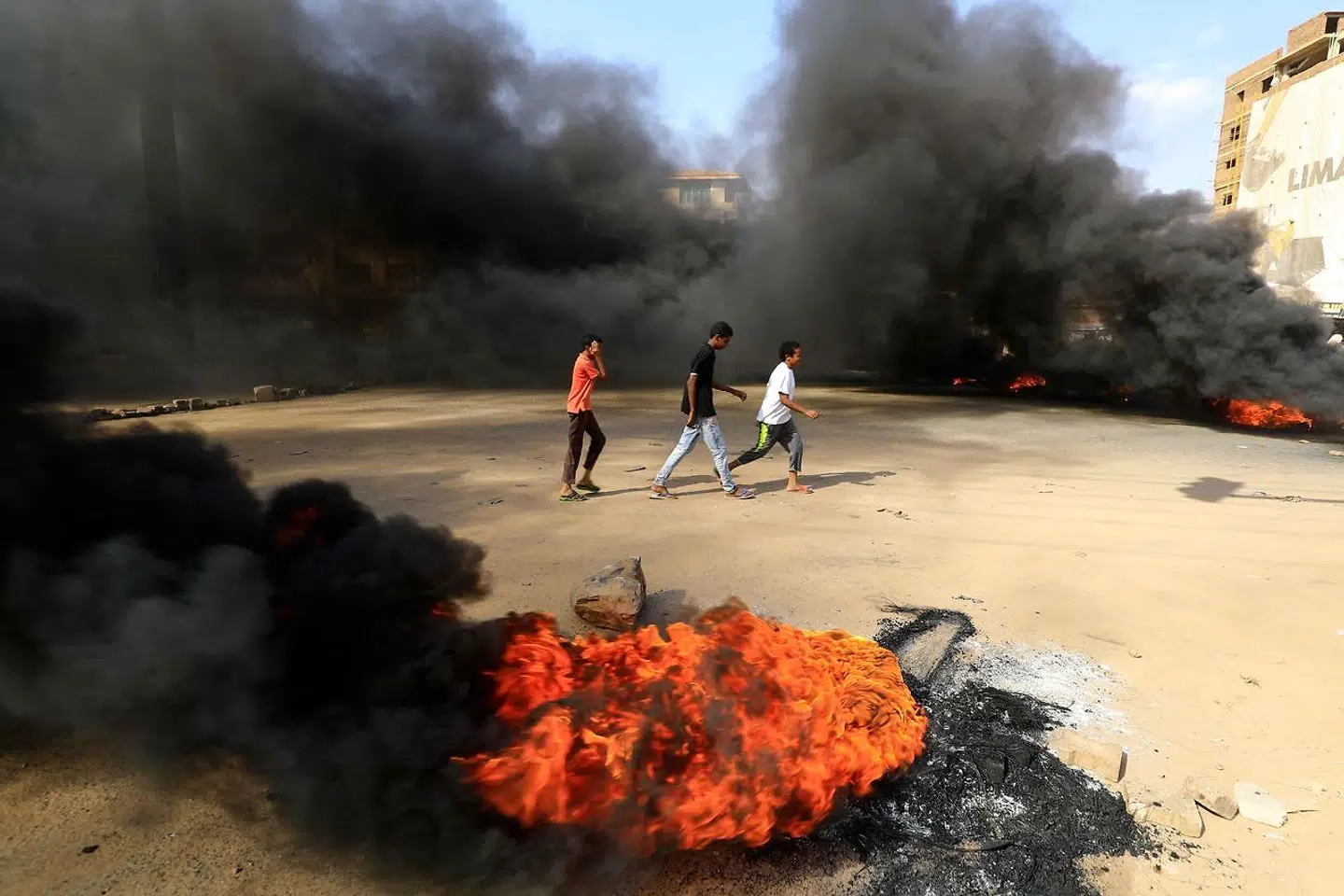 Unge demonstranter går på gaden og brænder dæk for at blokere vejen i hovedstaden Khartoum. (Photo by AFP)