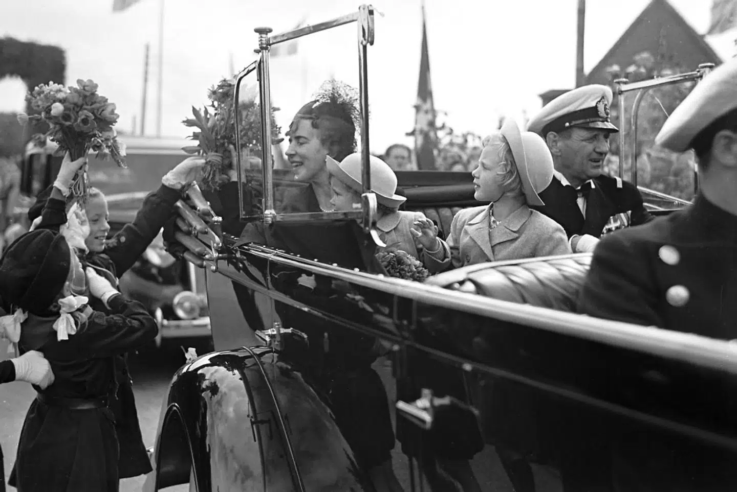 Kongefamilien ankommer til Gråsten i1947, året før ulykken. Kong Frederik 9., dronning Ingrid, prinsesse Margrethe og prinsesse Benedikte får blomster, mens de kører gennem byen i bil.