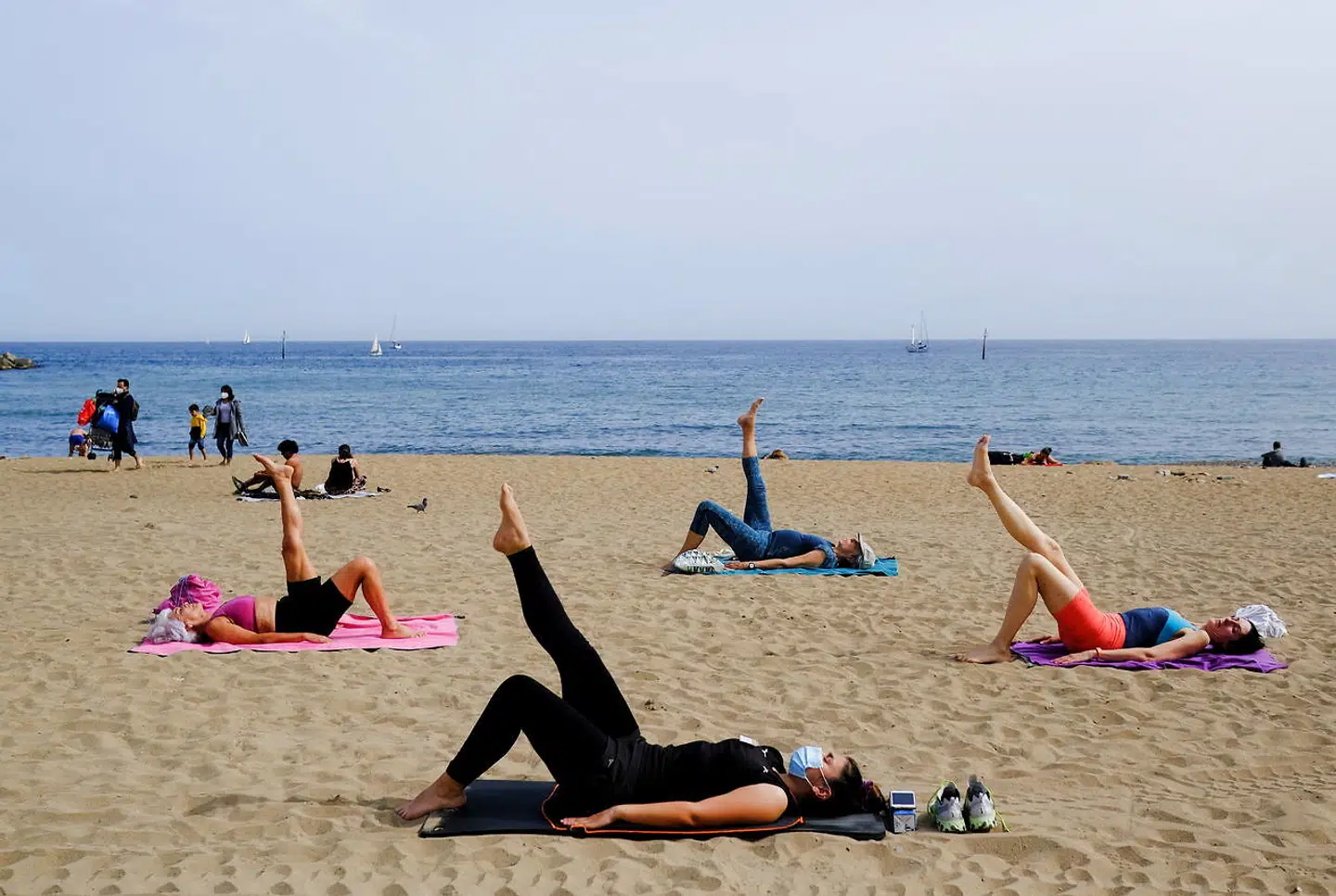 Et yogahold er i fuld gang på den centrale Barceloneta-strand. Under pandemiens begrænsning af indendørs fritidsaktiviteter rykkede mange ud i parker og på strande, hvor der i turisternes fravær har været god plads.