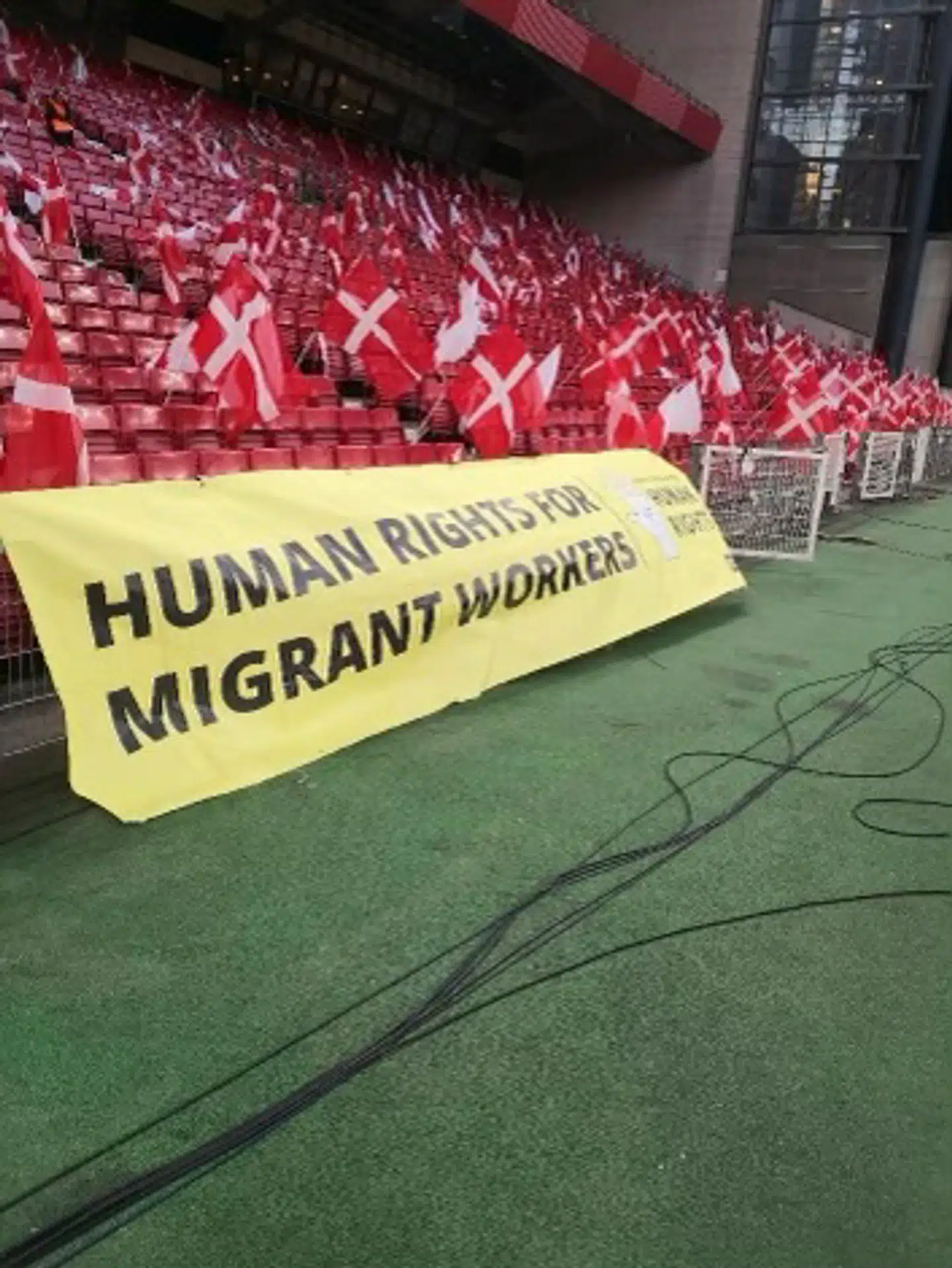 DBUs kommunikationschef, Jakob Høyer, bifalder dette banner, som nogle fans havde taget med i Parken. Banneret hylder kampen for bedre rettigheder til de migrantarbejdere, som arbejder i Qatar.