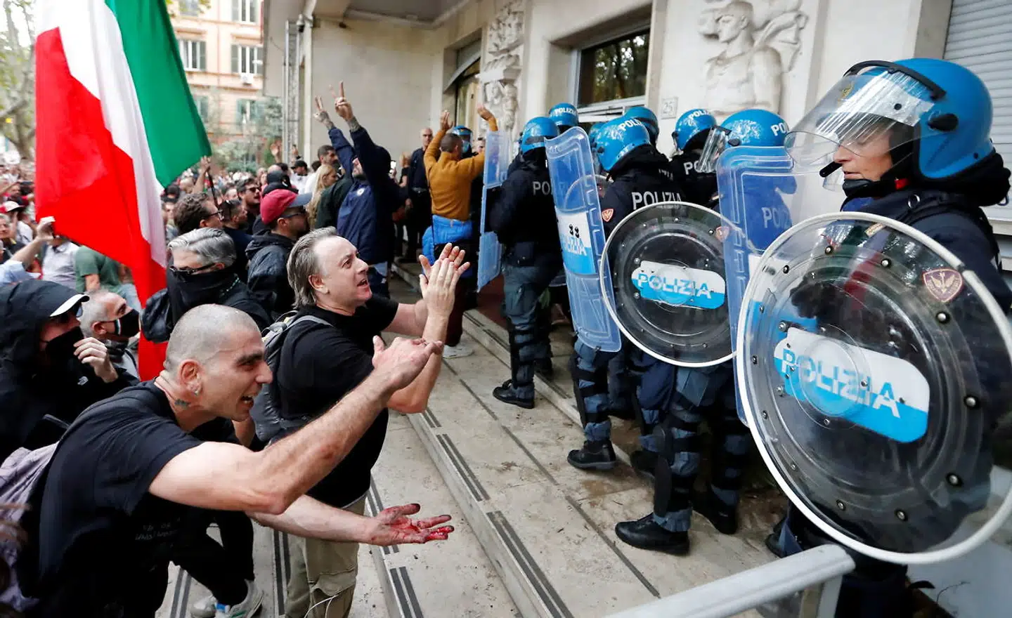 En håndfuld betjente forsøger at beskytte fagforeningen CGILs hovedsæde under lørdagens uroligheder. Det lykkedes ikke, og højreekstreme demonstranter drog hærgende gennem bygningen.