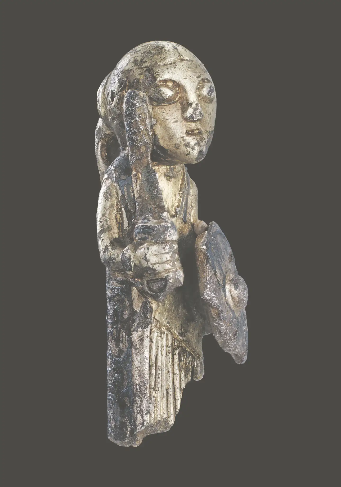 Denne kvindefigur med sværd og skjold er fundet på Fyn og forestiller sandsynligvis en valkyrie. Det lange hår er sat op i en hestehale med knude, og som kjole bærer hun en plisseret undersærk med en oversærk udover. Illustration fra bogen.