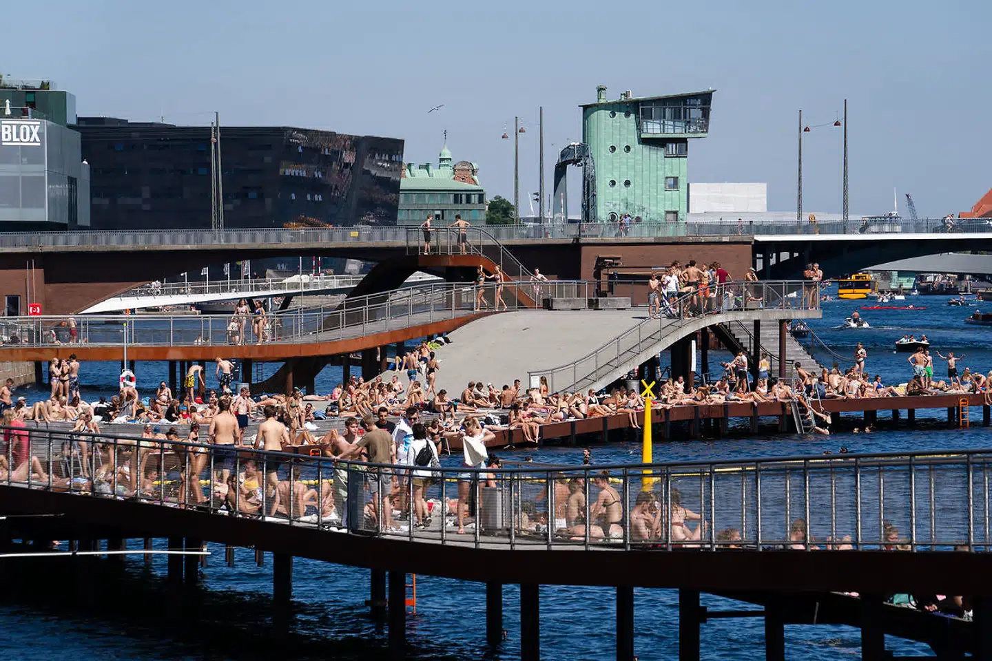 Personer i solen på Kalvebod Bølge over for Islands Brygge i København. Når DMI varsler høj temperatur, strømmer folket gerne ud. Men kan man altid regne med vejrudsigten?