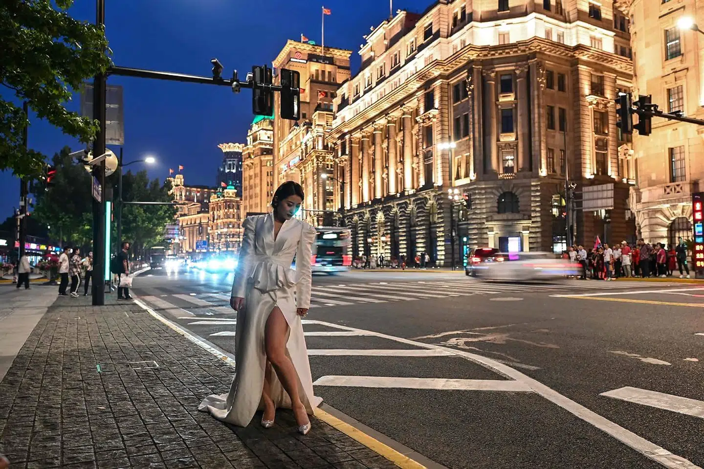 En kvinde poserer ved The Bund i millionbyen Shanghai, hvor nogle af verdens højeste skyskrabere er opført, og hvor de store luksusbrands dyster om at lokke de rige kinesere ind i butikkerne. Nu vil Xi Jinping have, at »kapitalen skal tjene folket«.