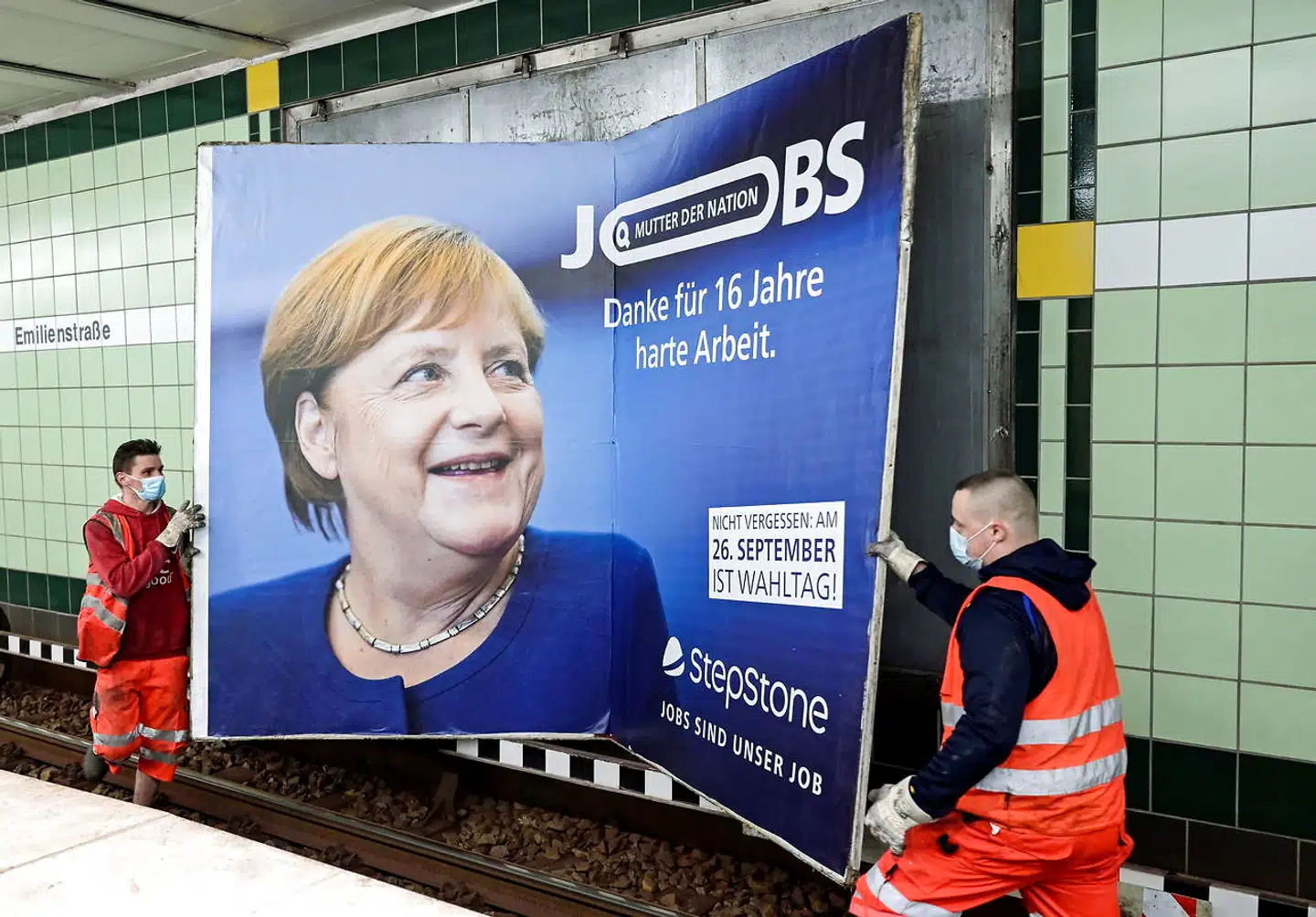 Arbejdere fjerner en reklame, der takker Angela Merkel for 16 års hårdt arbejde.