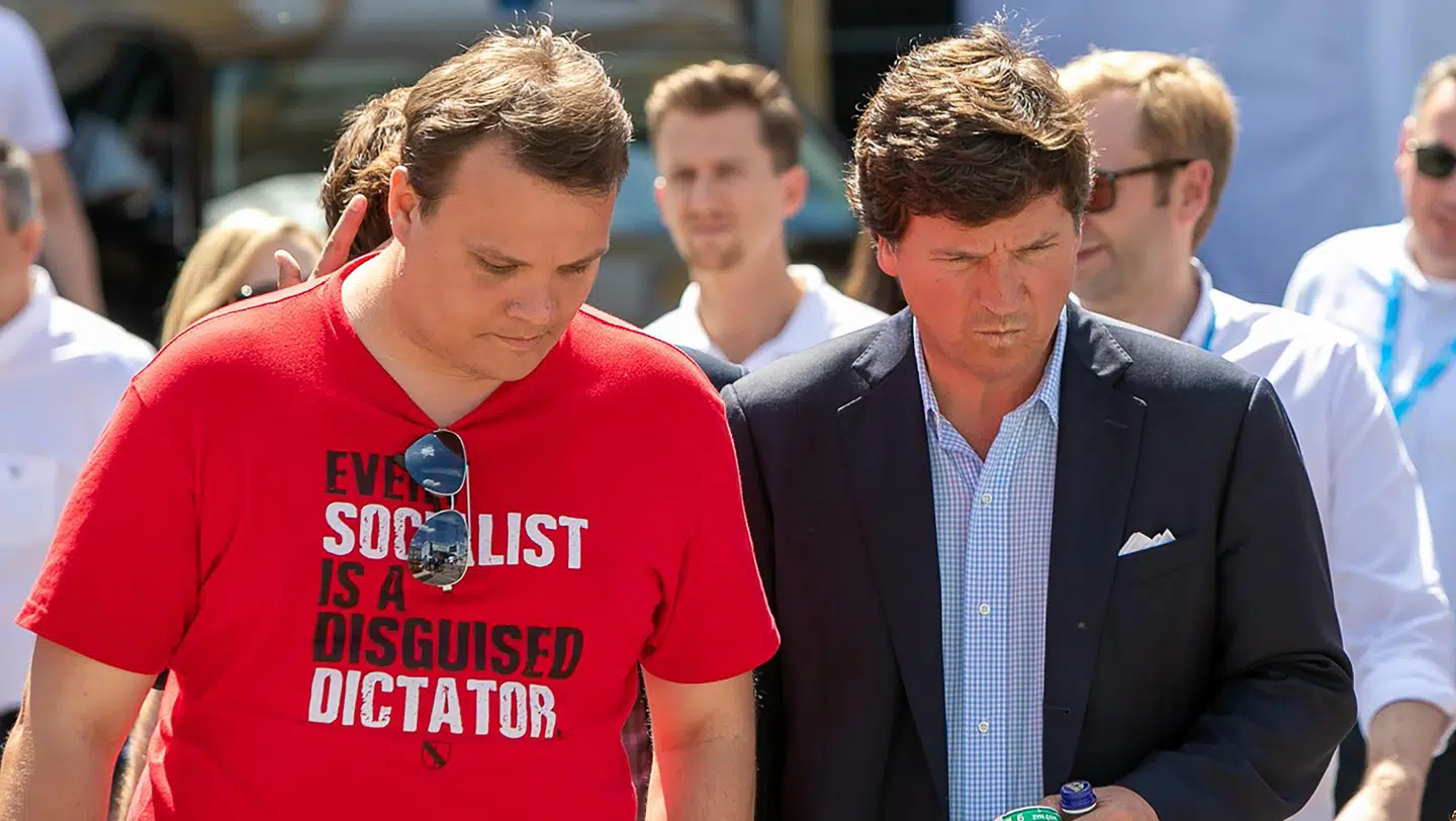 Tucker Carlson bliver fulgt til scenen i den ungarske by Esztergom af en af de lokale arrangerører. PR-foto