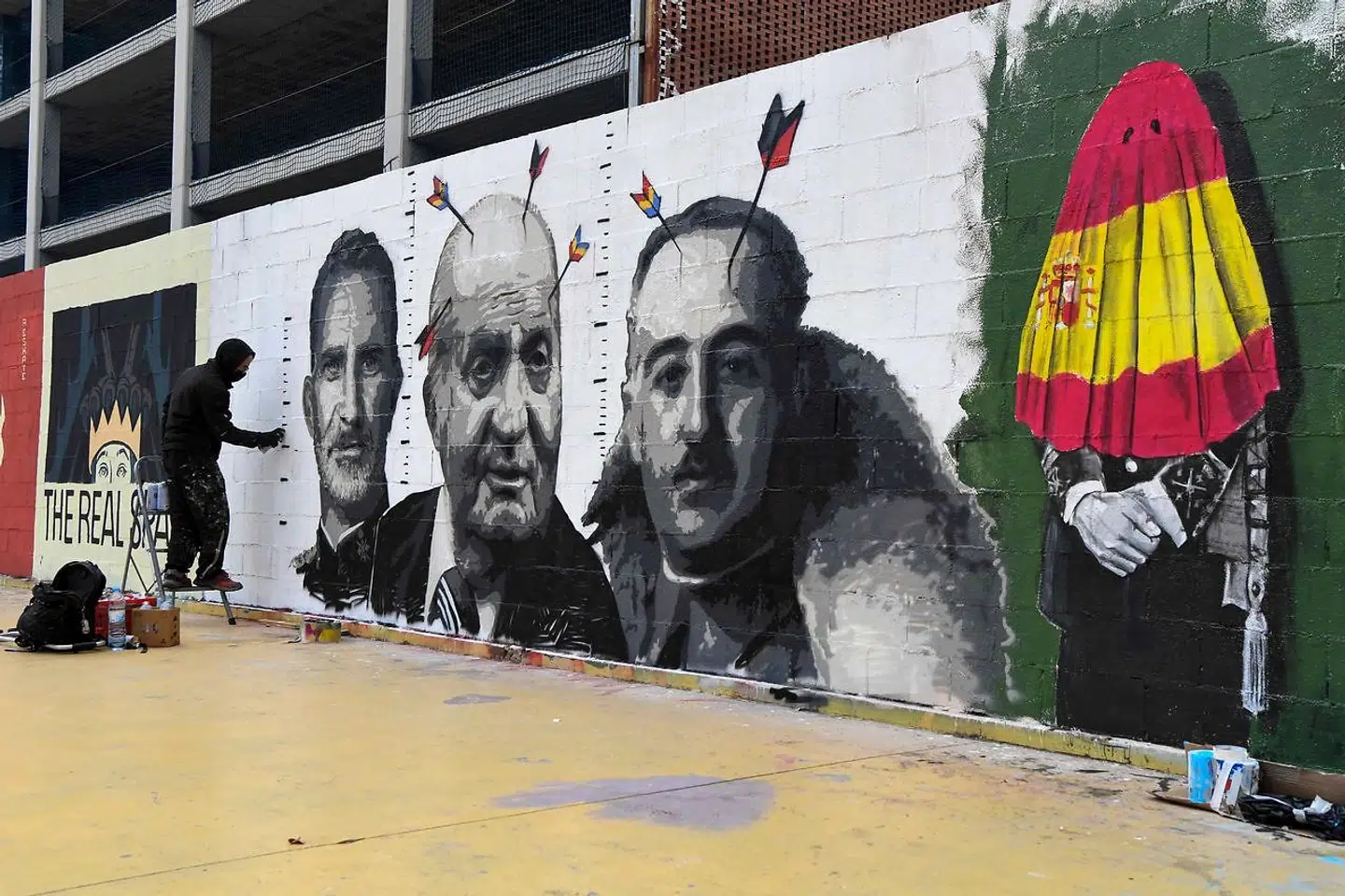 Spanske gadekunstnere har kronede dage med de mange skandaler omkring det spanske kongehus. Her er Roc BlackBlock i gang med at portrættere Juan Carlos 1. omgivet af sin søn, Felipe 6., og Spaniens mangeårige højreekstreme diktator, Francisco Franco.