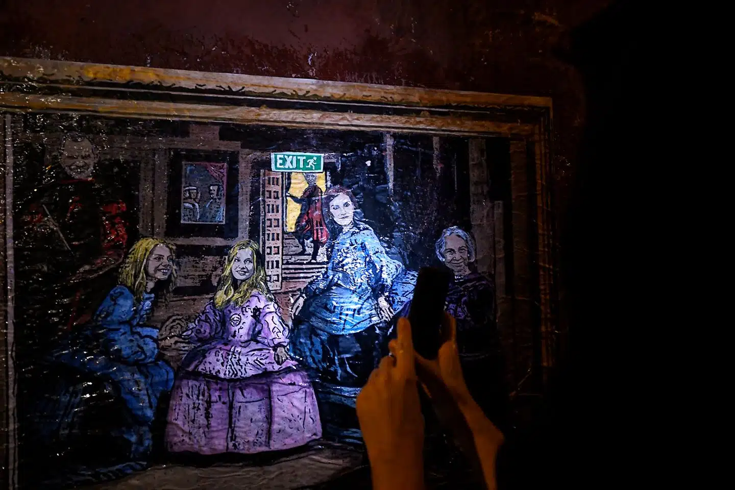Gadekunstneren TVBoys sarkastiske coverversion af Diego Velázquez' berømte maleri »Las Meninas« er en kommentator til Juan Carlos' eksil. Det er ekskongen under exitskiltet.