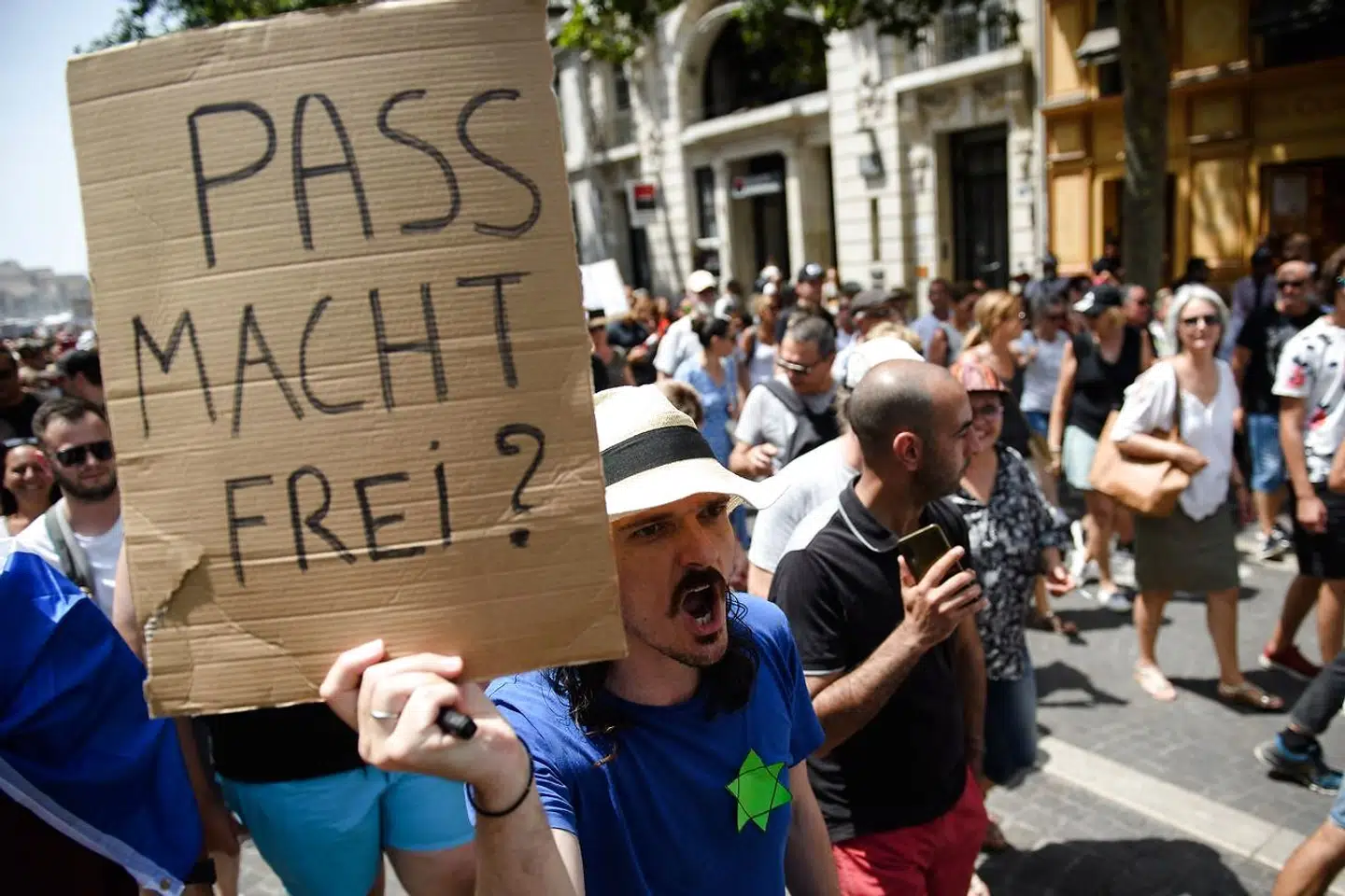 En demonstrant i Marseille protesterer mod indførelsen af coronapas, der søndag blev vedtaget i det franske parlament, med en parafrase over kz-lejrenes motto.