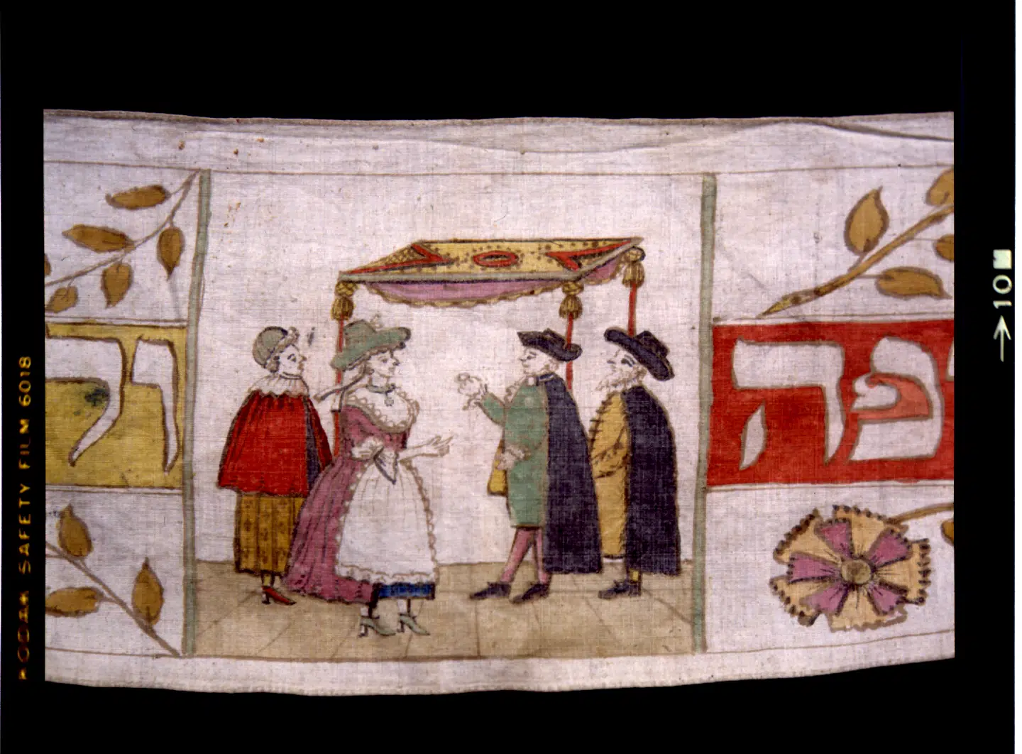 Den dansk-jødiske historie har en ubrudt 400-årig historie i modsætning til de fleste andre jødiske samfund, der blev udslettet. Blandt de pragtfulde genstande er 250 torah-vimpler tilbage fra 1700-tallet. Disse tre meter lange lærredsvimpler blev givet til synagogen, når en dreng blev født, og på den malede man motiver, som man ønskede for barnet. Den viste illustration viser et bryllup under bryllupsbaldakinen. Foto: Dansk Jødisk Museum.