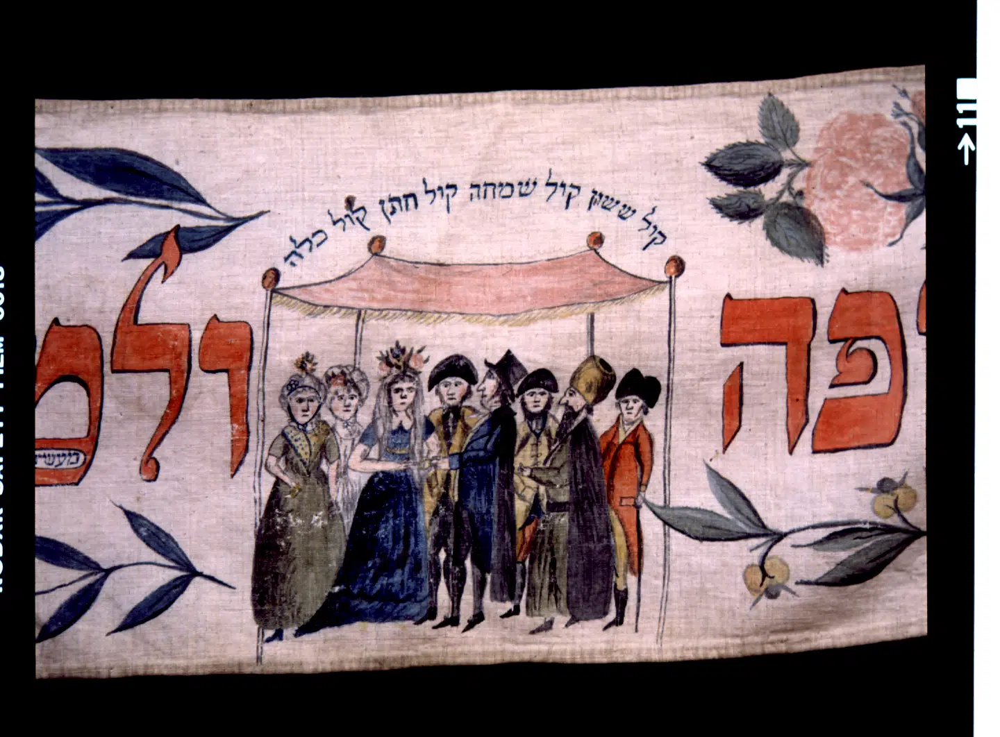 Den dansk-jødiske historie har en ubrudt 400-årig historie i modsætning til de fleste andre jødiske samfund, der blev udslettet. Blandt de pragtfulde genstande er 250 torah-vimpler tilbage fra 1700-tallet. Disse tre meter lange lærredsvimpler blev givet til synagogen, når en dreng blev født, og på den malede man motiver, som man ønskede for barnet. Den viste illustration viser et bryllup under bryllupsbaldakinen. Bemærk at rabbineren med pelshue og sort kaftan er traditonelt påklædt, mens de andre er med på moden fra 1800-tallets begyndelse. Foto: Dansk Jødisk Museum.