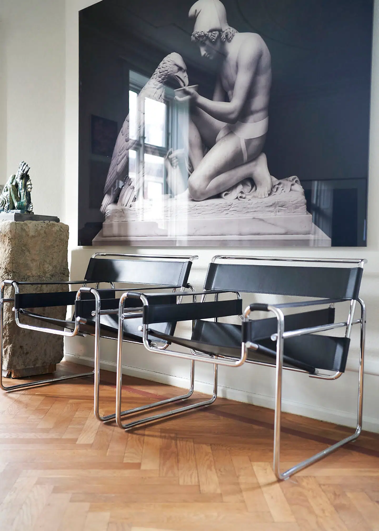 På væggen hænger et værk af Elmgreen & Dragset. Ved siden af de to stole står en plint af Fos, som var udstillet på hans soloudstilling på Kunsthal Charlottenborg. Ovenpå er en skulptur af Martin Brandt Hansen.