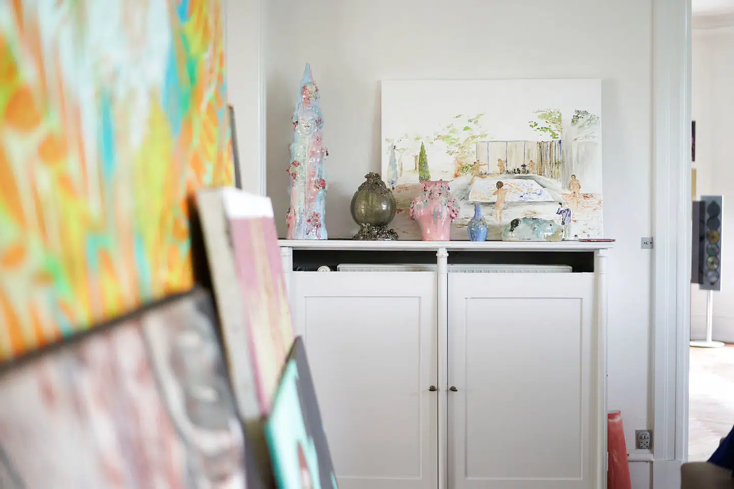 På hylden står en række værker af Klara Lilja, som Maria Friis opdager i forbindelse med bachelorudstillingen på Det Kongelige Danske Kunstakademi. Senere får Klara Lilja en soloudstilling i kælderen hos V1 Gallery, hvor Maria Friis køber en stor del af udstillingen. Bag Klara Liljas keramik er et værk af Lea von Wintzingerode.