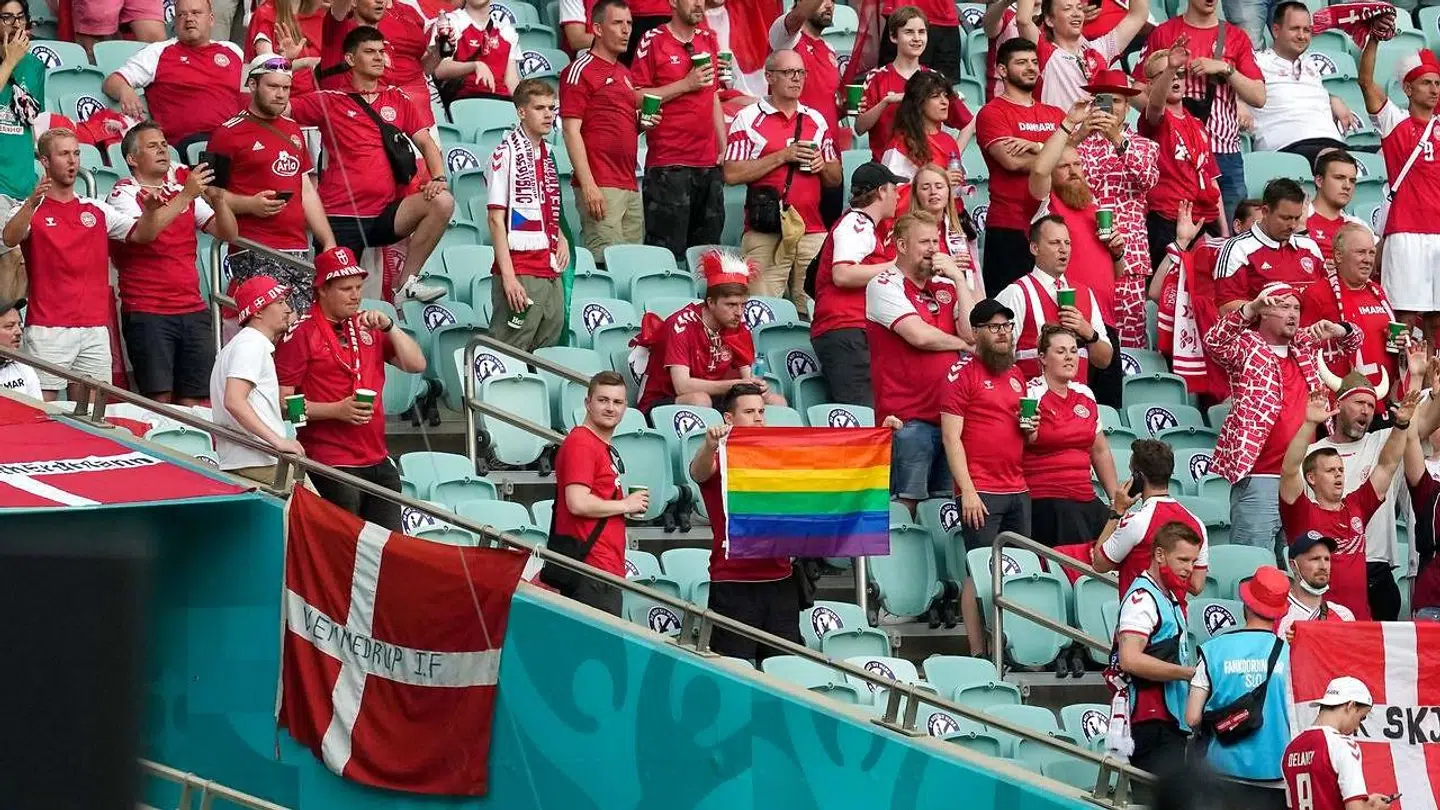 En dansk fan holder et regnbueflag op på stadion i Baku.