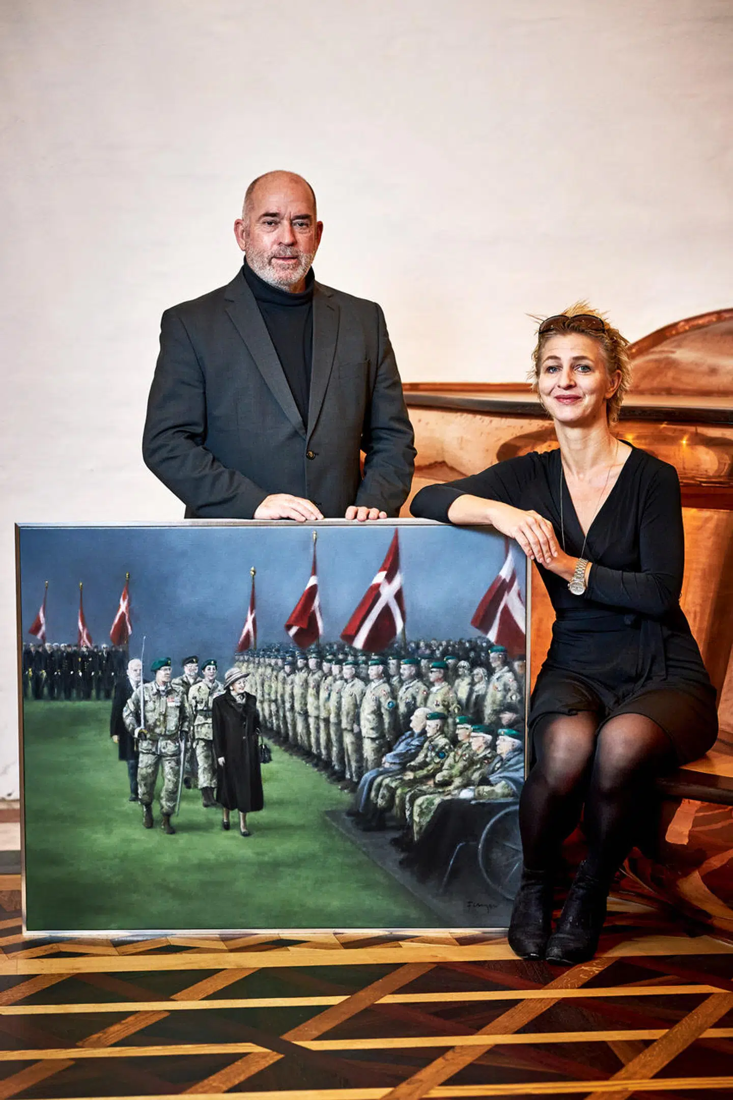 Maleri af dronning Margrethe, der inspicerer Hjemmeværnet i forbindelse med Hjemmeværnets 70 år-jubilæum i 2019. Ved siden af værket kunstmalereren Mathilde Fenger og formand for Hjemmeværnsfonden Søren Espersen (DF).