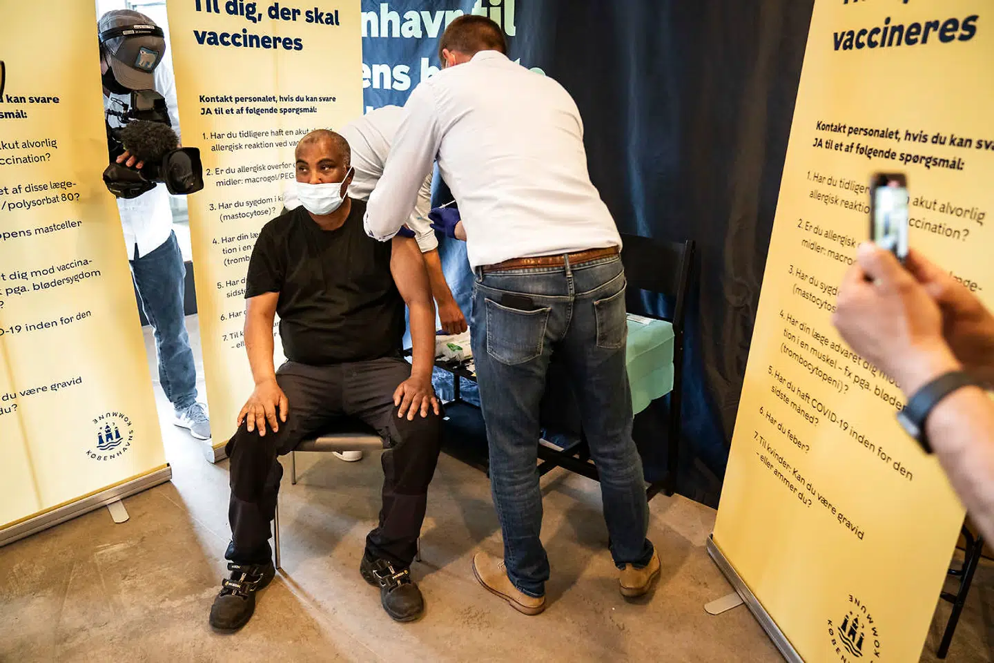 Ahmad Abdi Hassan modtager en vaccine fra Søren Brostrøm, der mandag gav en hjælpende hånd med at vaccinere i Tingbjerg Pensionist Center i København.