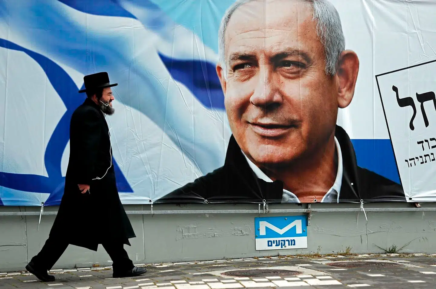 En ortodoks jøde går forbi en valgplakat med et portræt af Benjamin Netanyahu. Efter fire valg på to år er Netanyahu nu ikke længere premierminister. Israels nye regering bliver tvunget til moderation og kompromiser for at overleve, skriver Pierre Collignon i denne leder: »Det er en anden dynamik end den, som har drevet Benjamin Netanyahu.«