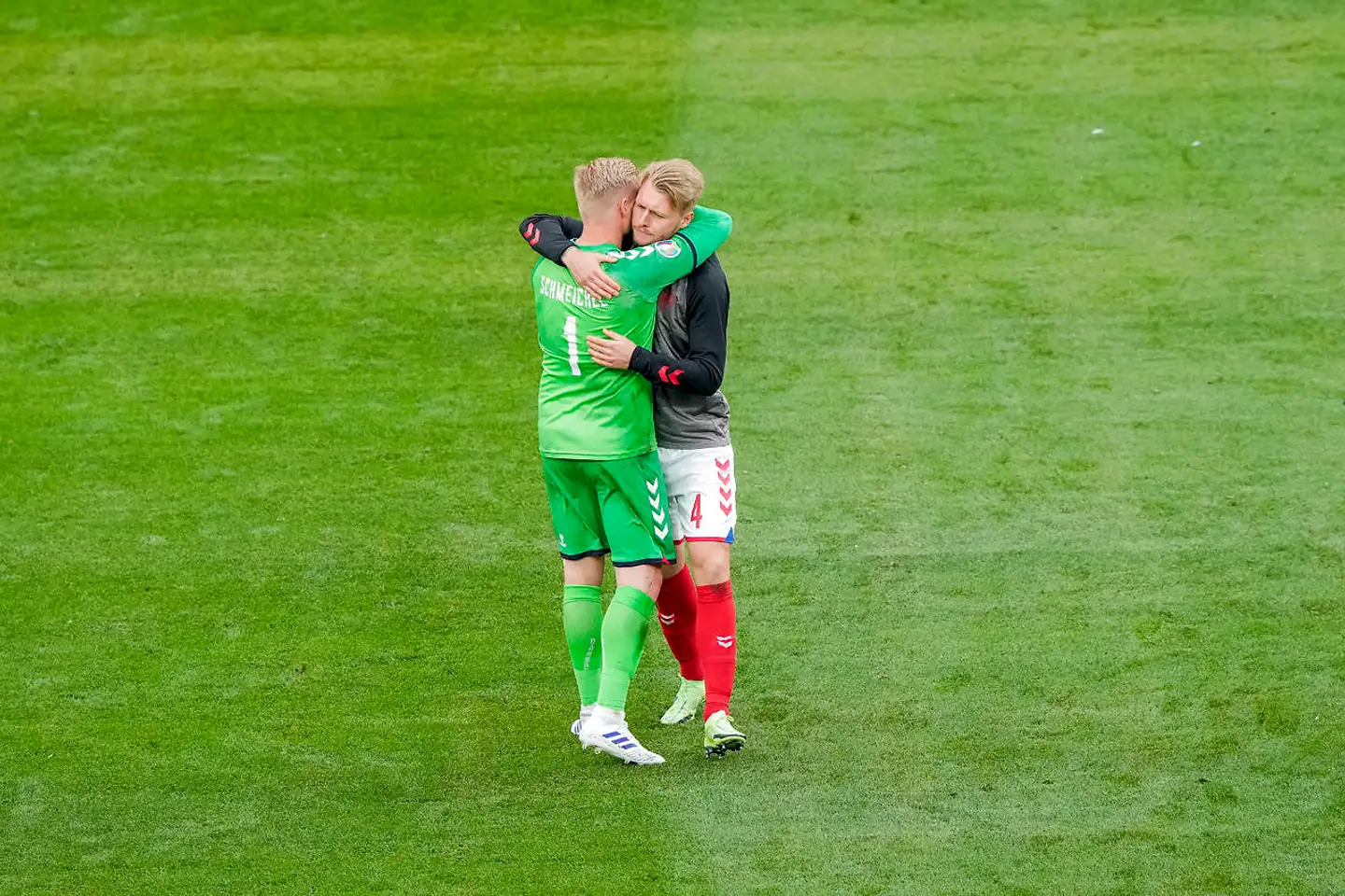Kasper Schmeichel giver Simon Kjær et kram, inden lørdagens kamp genoptages. Da de chokerede holdkammerater dagen efter var i kontakt med Christian Eriksen, havde han overskud til en frisk bemærkning.