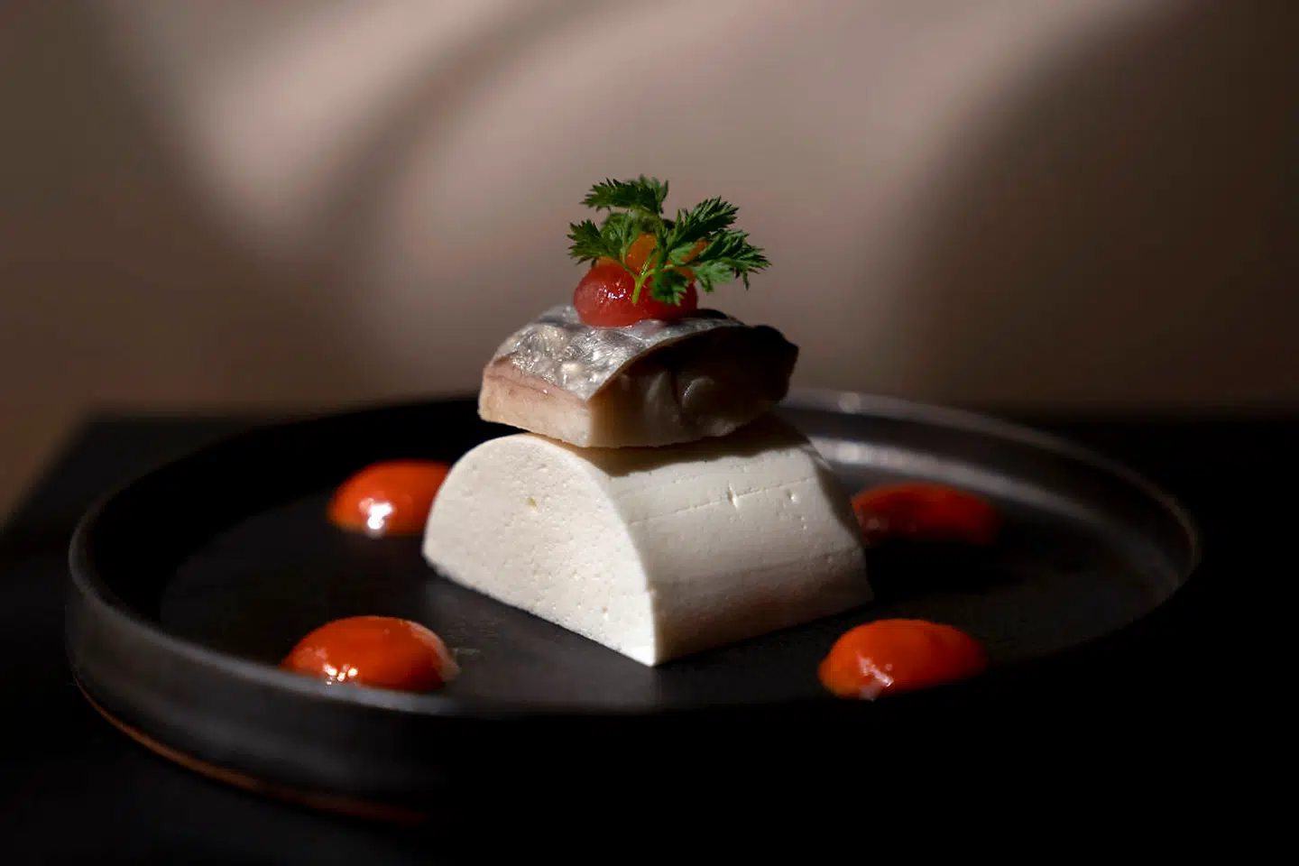 Makrel syltet i hyldeblomst på en mousse af peberrod, toppet af en broken gel på rosa grape med dutter af karryspicet tomatcoulis på siden.