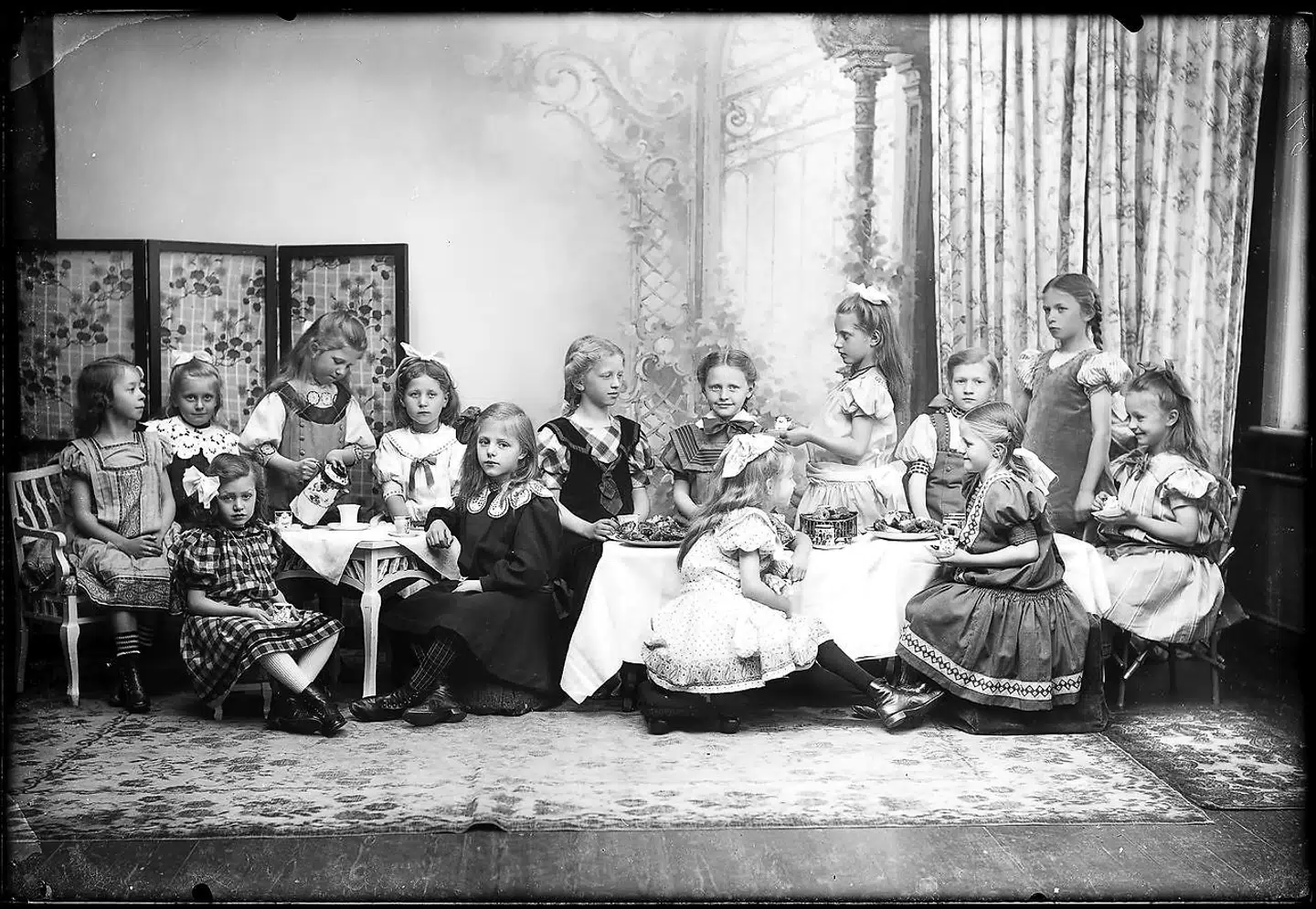 De to yngste klasser i Hjørring Private Pigeskole, 1908-1909. Kirstine Lund benytter sig her af en tableauæstetik, der er hentet fra malerkunsten. Personerne arrangeres i bestemte mønstre, der giver symmetri i fotografiet. Foto: Historisk Arkiv, Vendsyssel Historiske Museum.