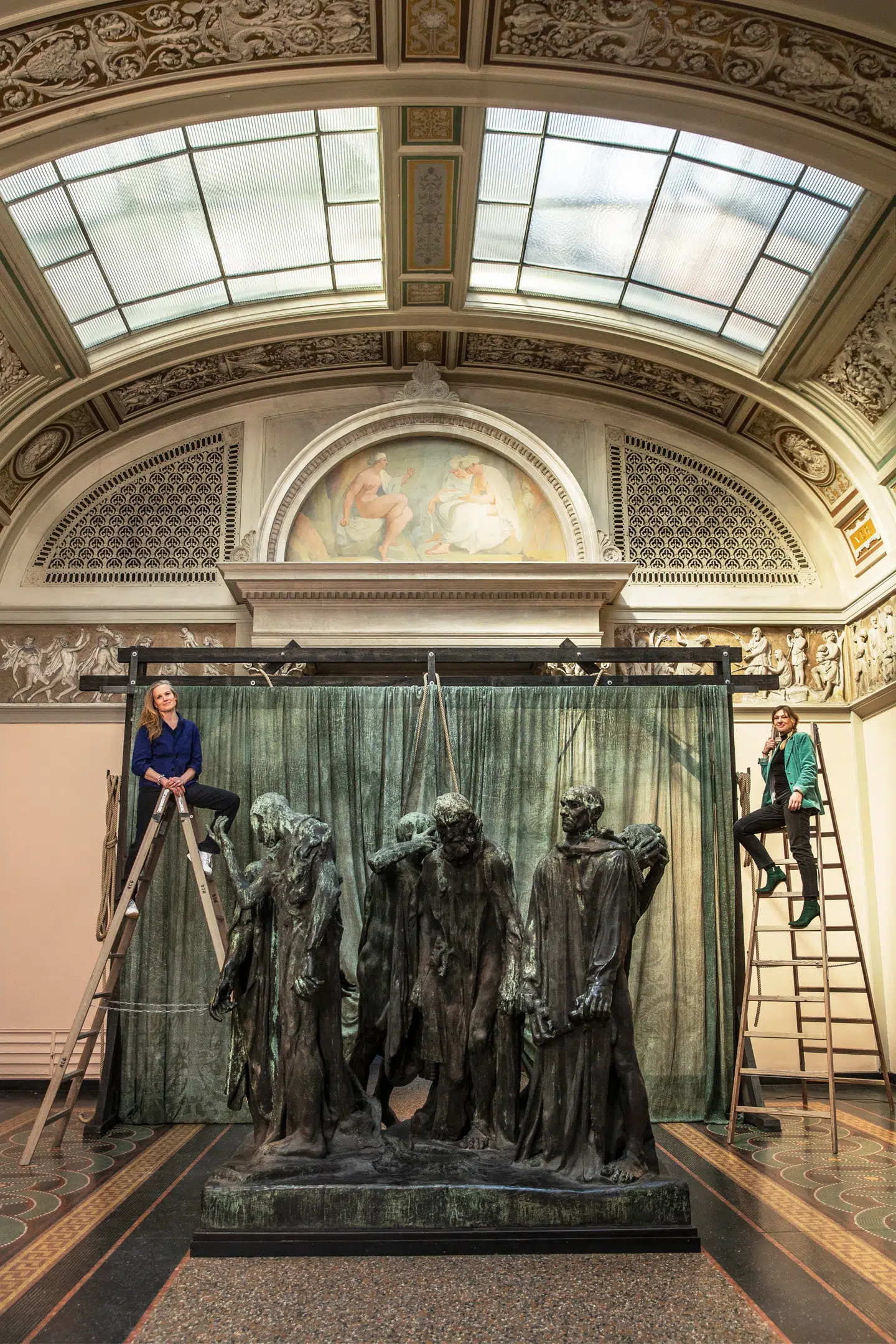 Mia Steensgaard og Anja Vang Kragh højt til hest. Under opsætningen af bagtæppet til ”Borgerne fraCalais” hev de to stiger ind i salen til et fotoshoot. Ingen stiger er brugt i en reel arbejdssammenhæng. Foto: Natacha Rydvald & Marc Fluri.