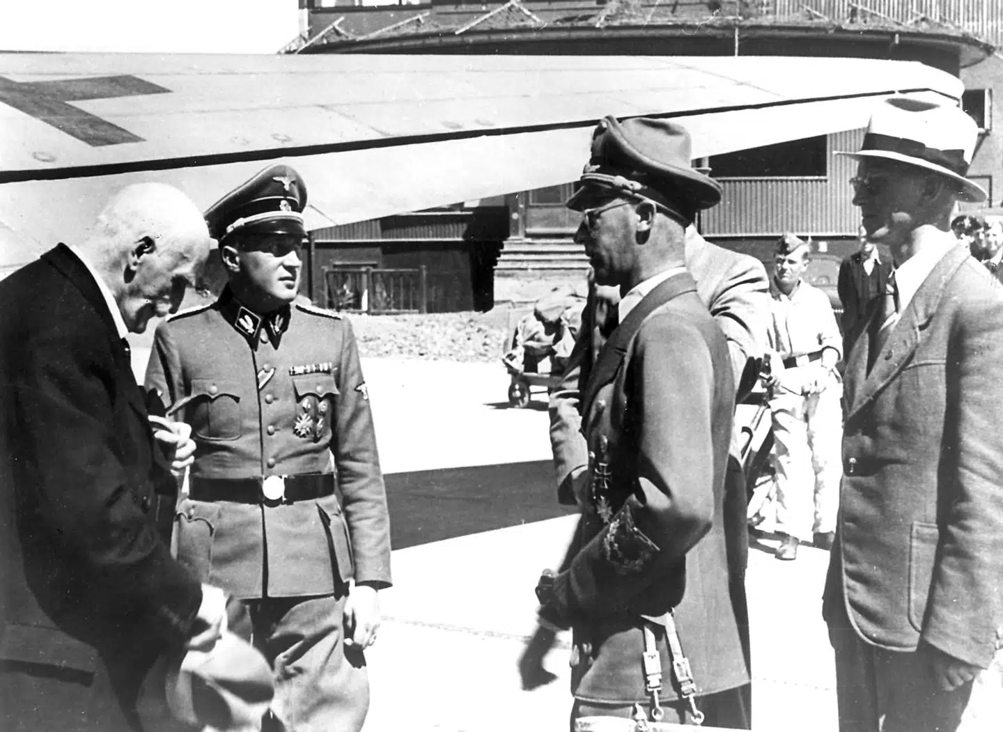 Knut Hamsun blev i stor stil brugt i frivilligt i den nazistiske propaganda. På Billedet ses: Forfatteren Knut Hamsun (længst til venstre) der modtages i lufthavnen Fornebu af Josef Terboven. Bag ham ministerialdirigent G.W. Mueller og pressechef Anders Beggerud.