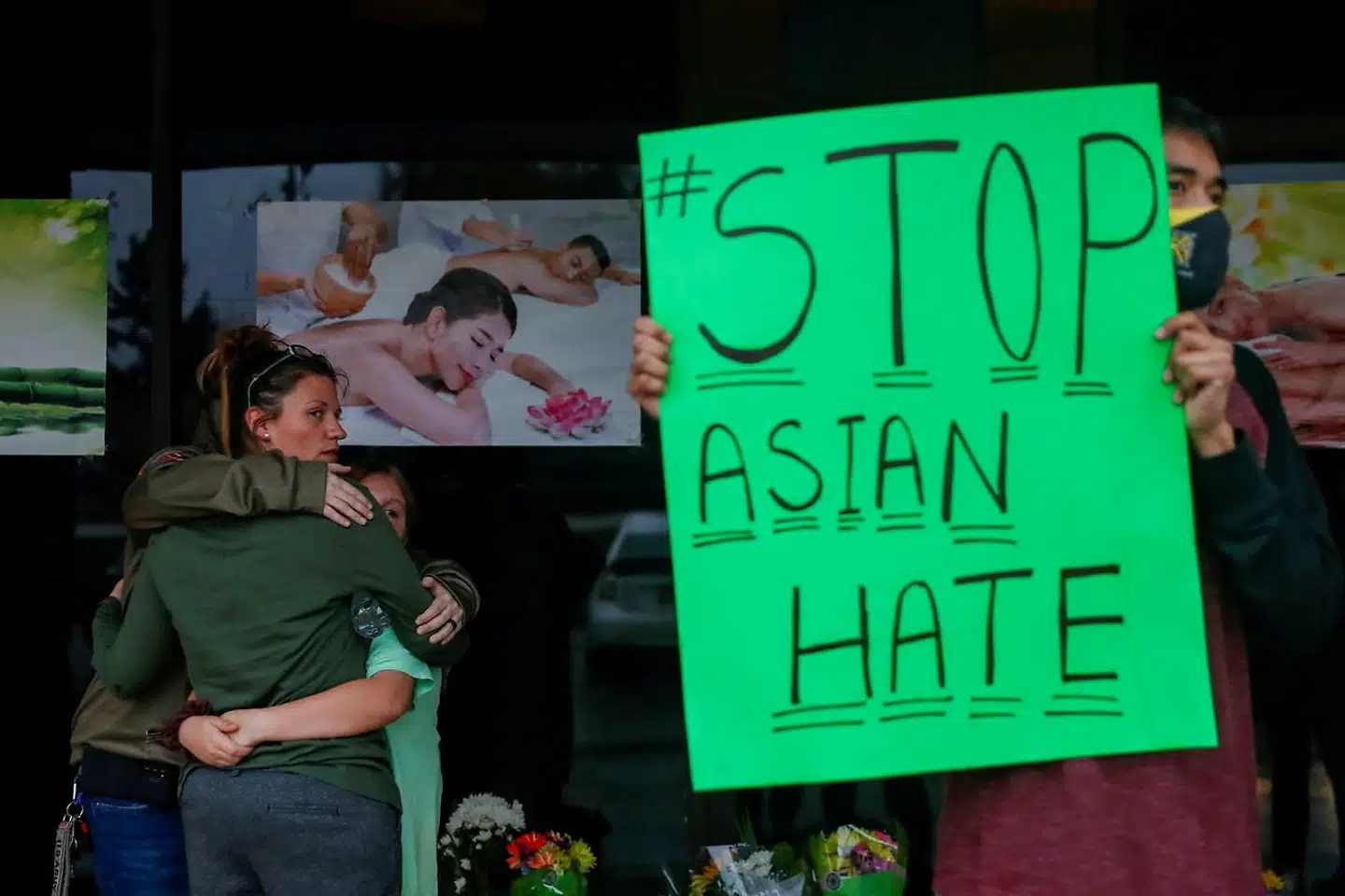 Foran massageklinikken Young's Asian Massage er flere personer forsamlet for at mindes ofrene for skyderierne. Skilte med ordene »#StopAsianHate« er dukket op flere steder.