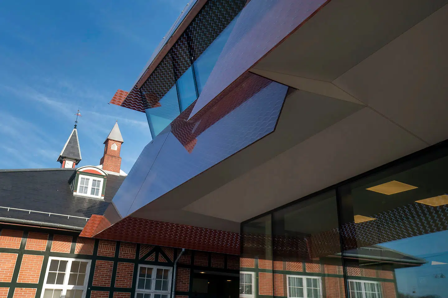 Med det nye rødbrune mønster på glaspladerne taler Østerport II meget bedre med den gamle station. De overlappende hjørnevanger er en original detalje, der elegant hilser på skønvirkestilen ved siden af.