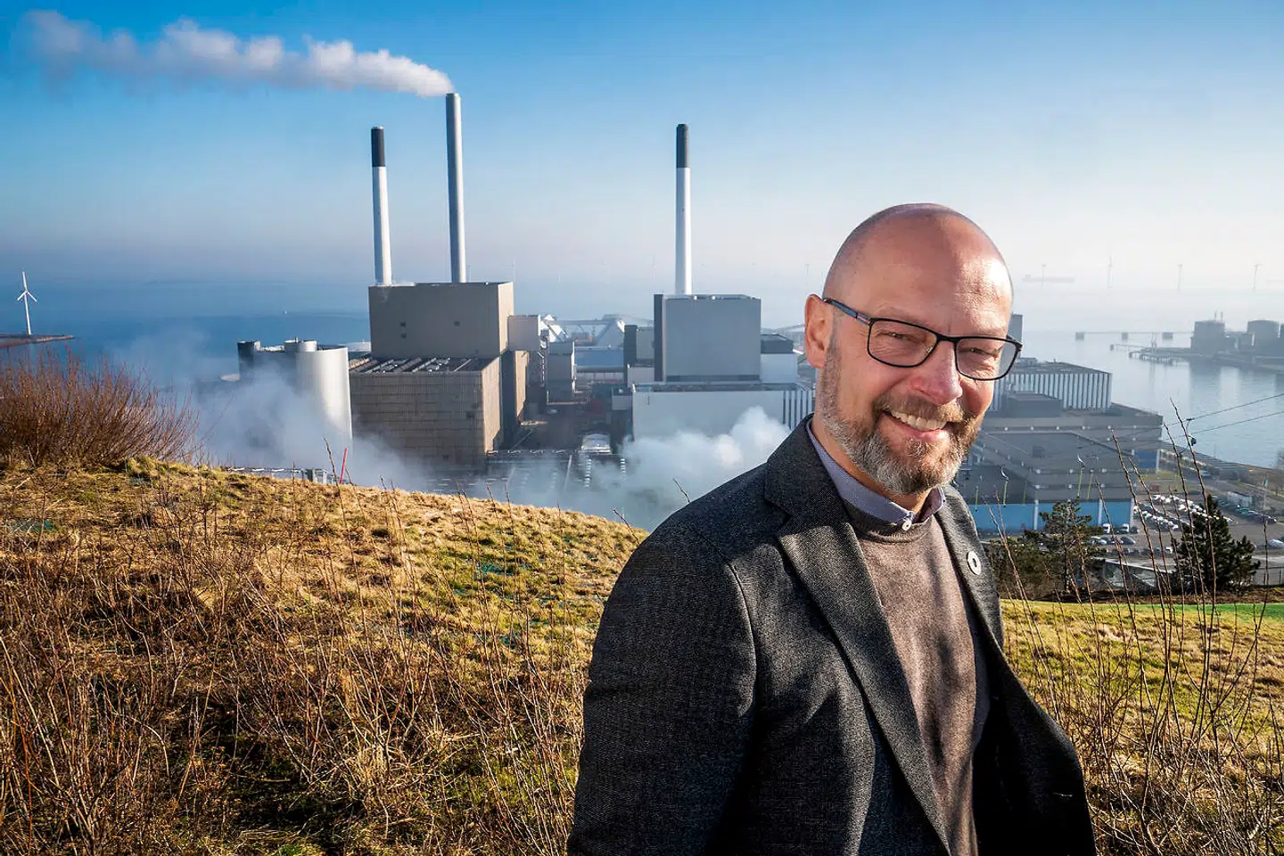 Direktøren for Amager Ressourcecenter (ARC), Jacob Simonsen, på toppen af Amager Bakke, hvor forbrændingen af restaffald kører på fuld tryk. I baggrunden for foden af skibakken ses Amagerværket, der også er en del af det nye klyngesamarbejde Carbon Capture Cluster Copenhagen.