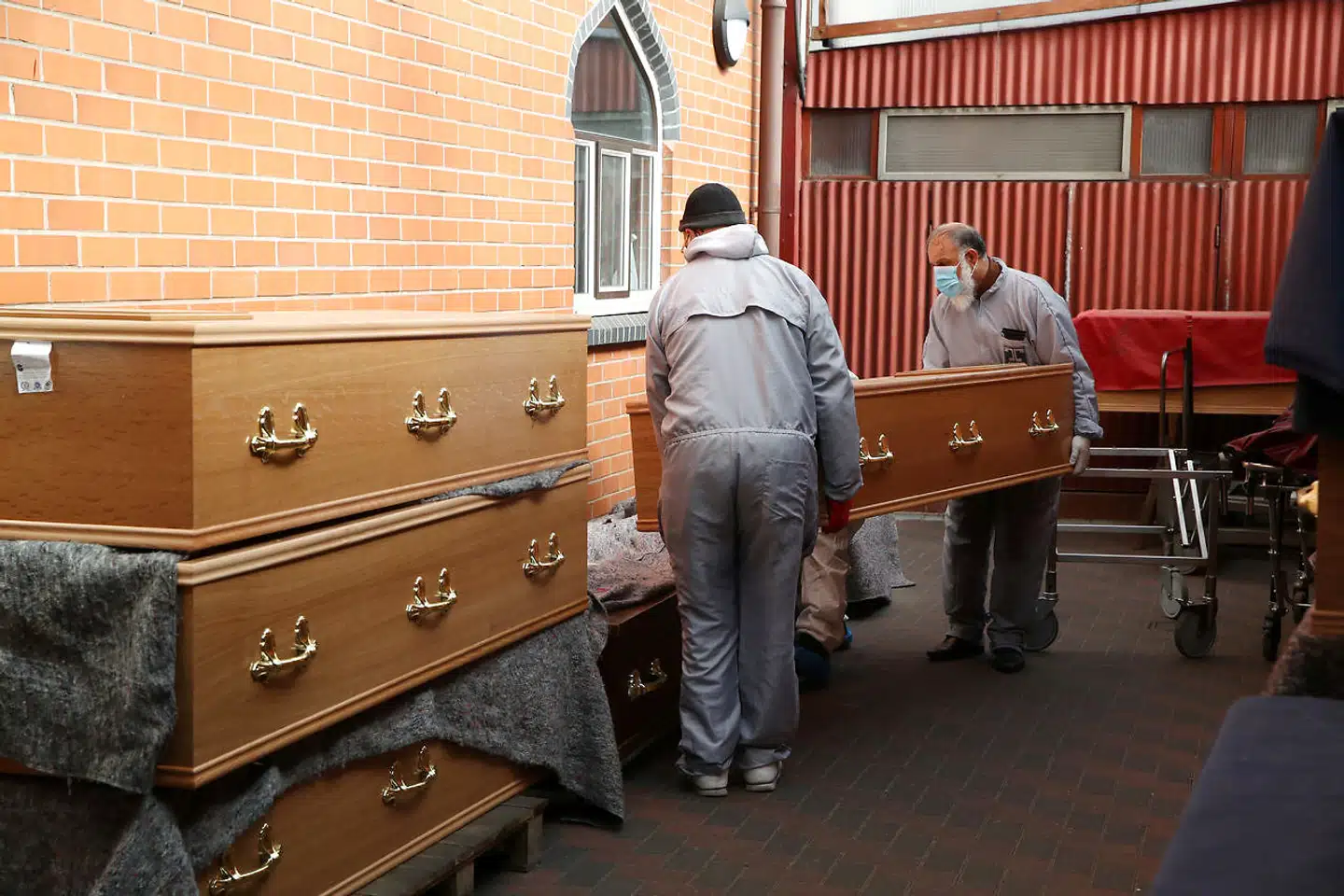 Arbejdere bærer kister ind i et af de midlertidige lighuse, som er oprettet i Storbritannien – for siden jul er de i forvejen foruroligende dødstal eksploderet. Boris Johnson får skylden, fordi han gjorde et stort politisk nummer ud af at »kæmpe for« at redde briternes ret til at holde jul. »Regeringen har blod på hænderne,« siger overlevende fra en familie, hvor fire familiemedlemmer døde efter en kort julekomsammen.