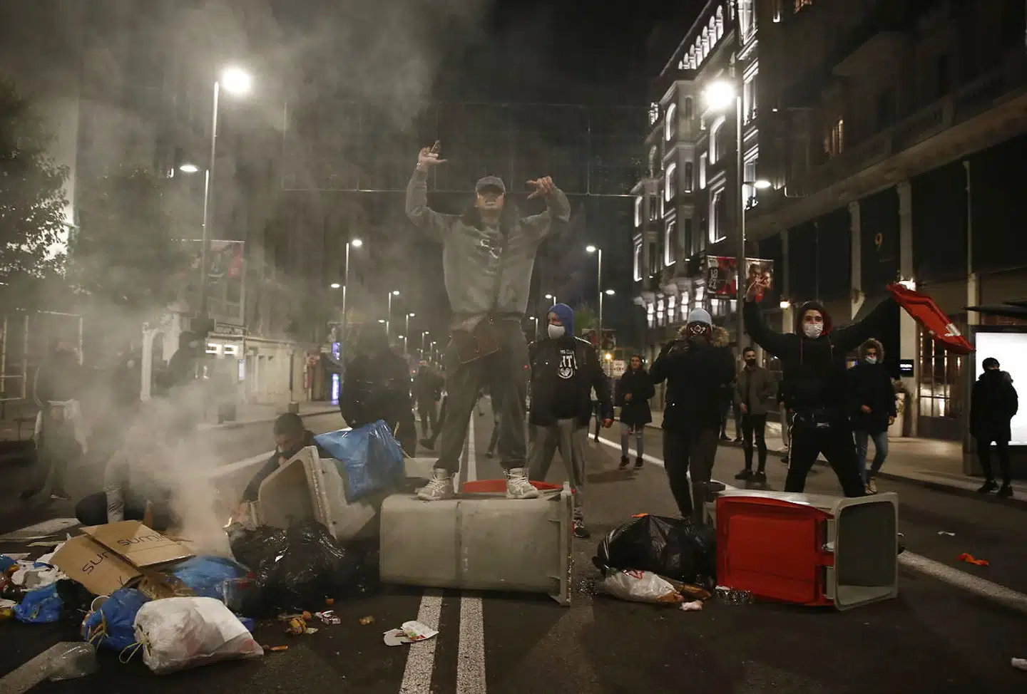 Demonstranter bygger barrikader med skraldespande under en demonstration mod udgangsforbud og andre forholdsregler i Madrid. Endnu er det ikke gået helt amok. Men frygten for, at det skal ske, er en af grundene til Spaniens »svenske« politik i kampen mod pandemiens anden bølge.