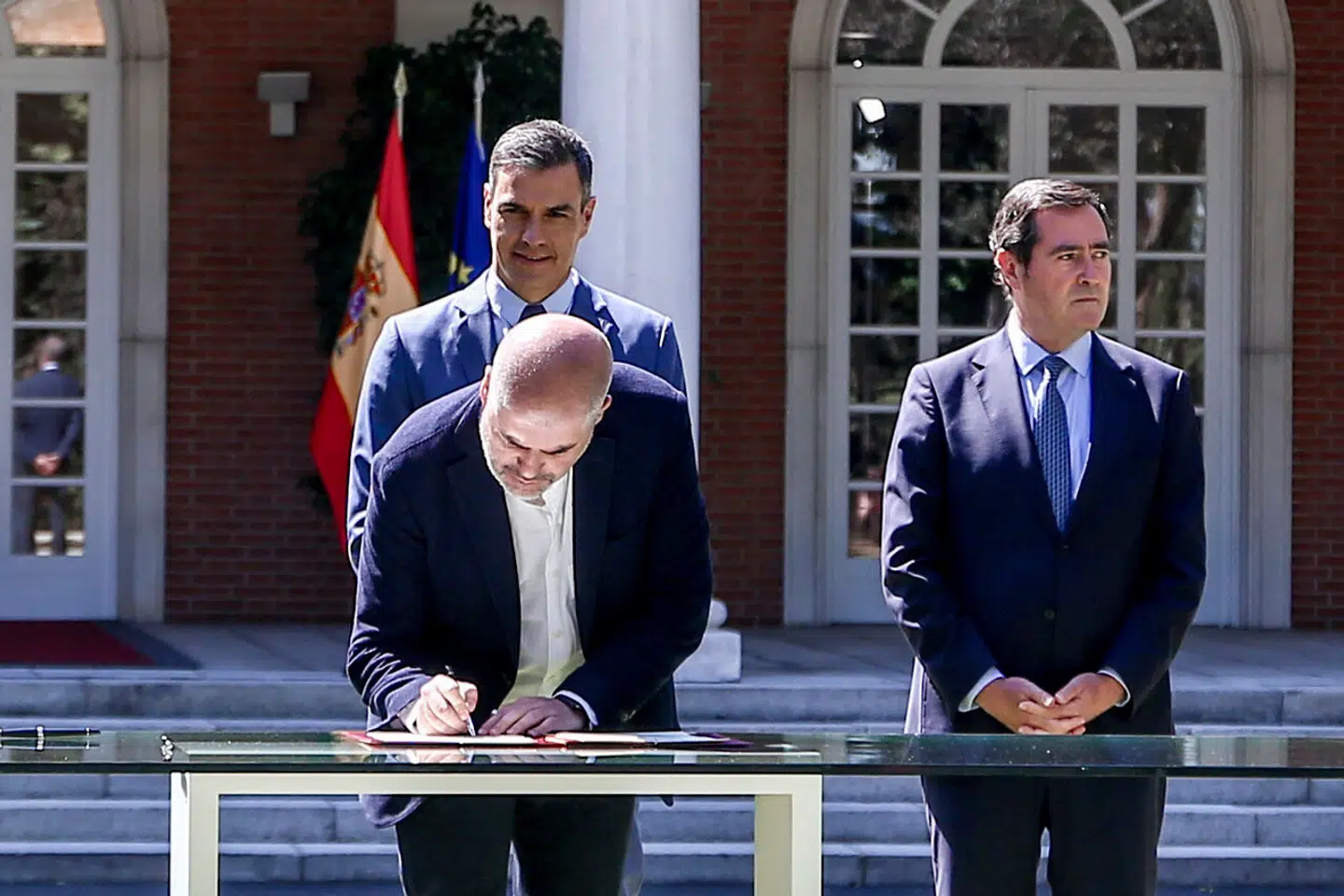 Repræsentanter for arbejdsmarkedets parter underskriver i juli 2021 aftalen om en reform af Spaniens pensionssystem, mens en smilende Pedro Sánchez ser til.