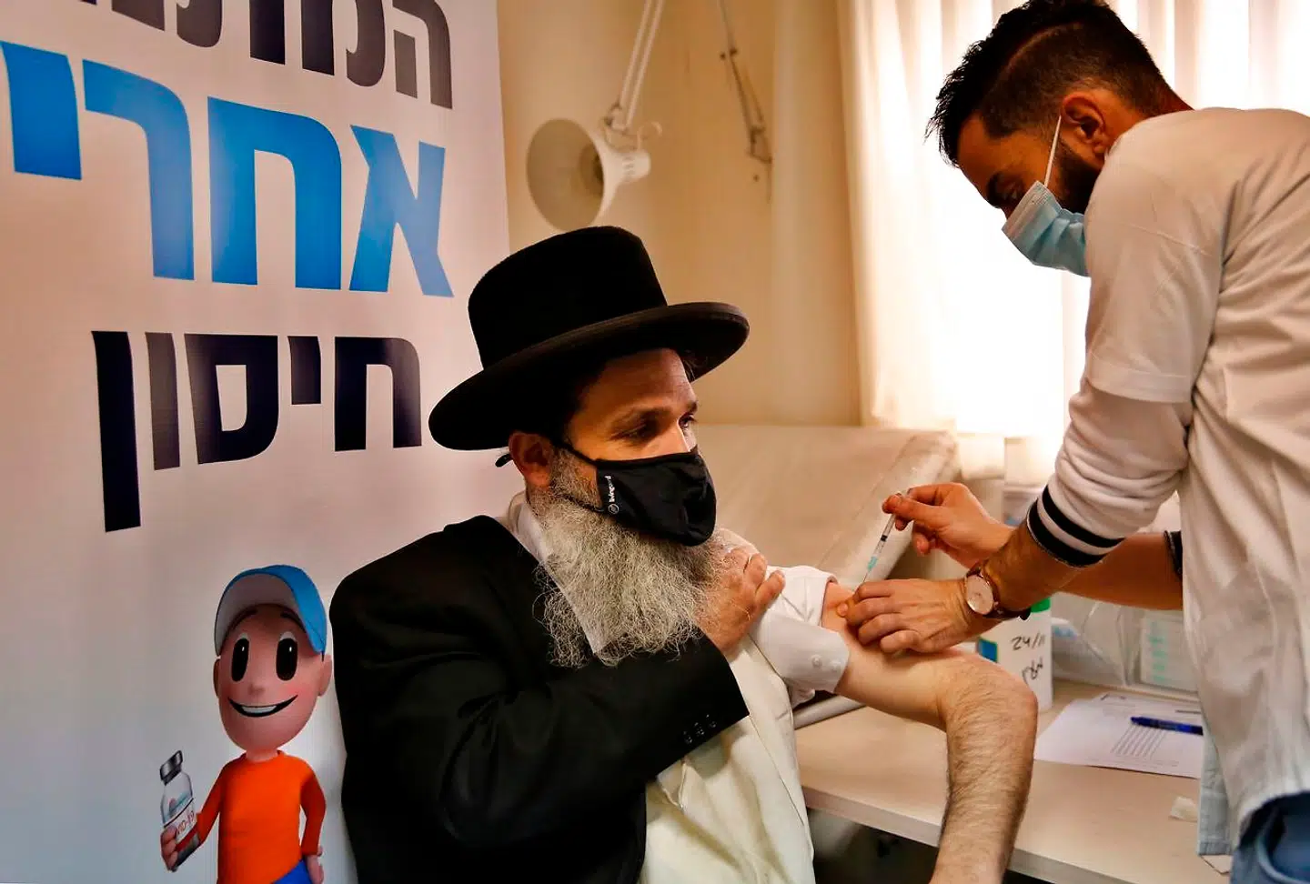 En glad lille dreng er logo for Israels foreløbig succesrige vaccinationskampagne. Her er det en ultraortodoks borger, som får sit stik i Bnei Brak nær Tel Aviv.
