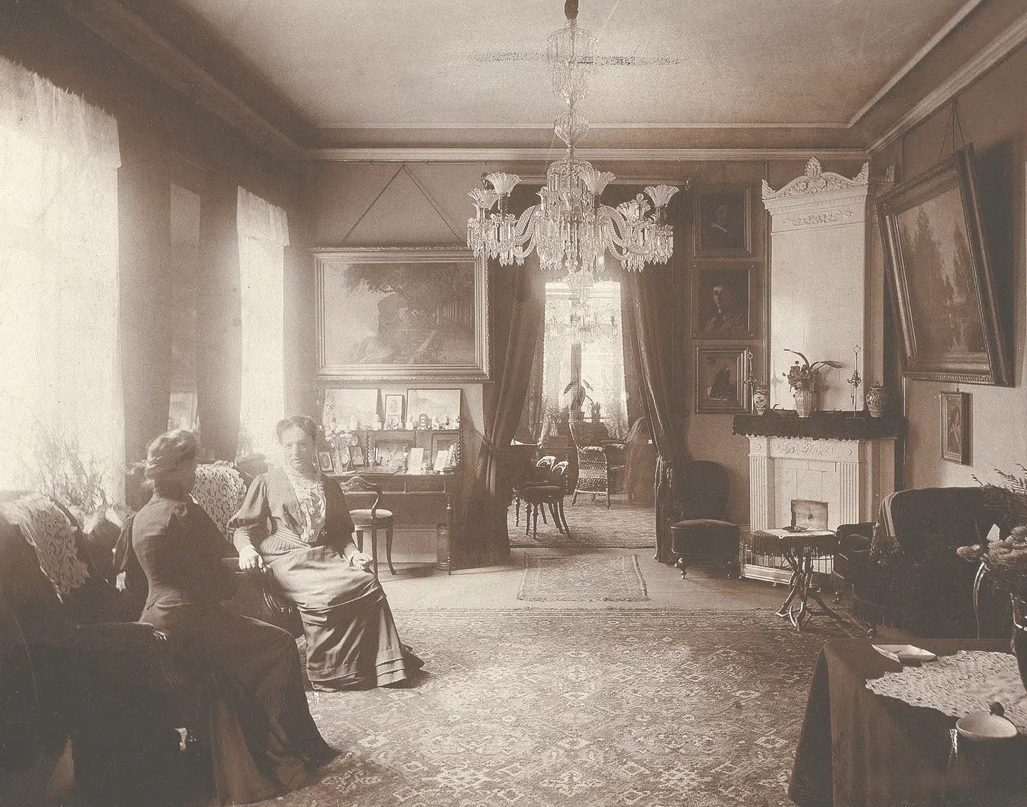 Familen Henriques' dagligstue i Tordenskjoldsgade 1 på første sal. Med ansigtet vendt mod kameraet sidder Anna Henriques. Stilen er fra 1800-tallets slutning.