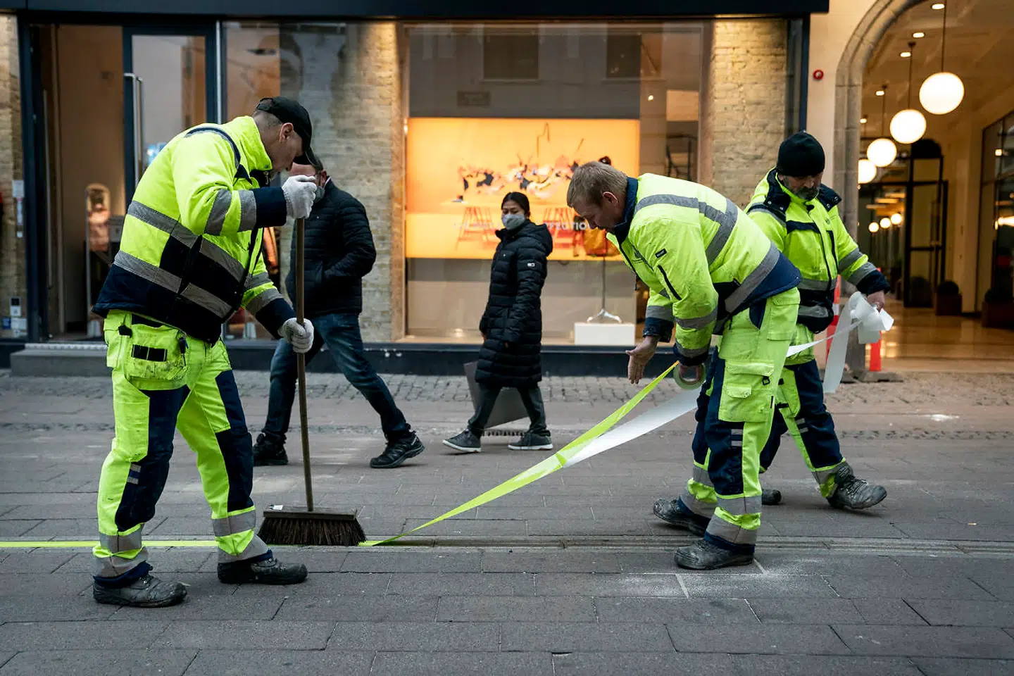 Københavns Kommunes vejarbejdere fra »stribeafdelingen«, som de selv kalder det, er ved at lægge tape i midten af Strøget. Det skal sikre, at de gående holder til højre.