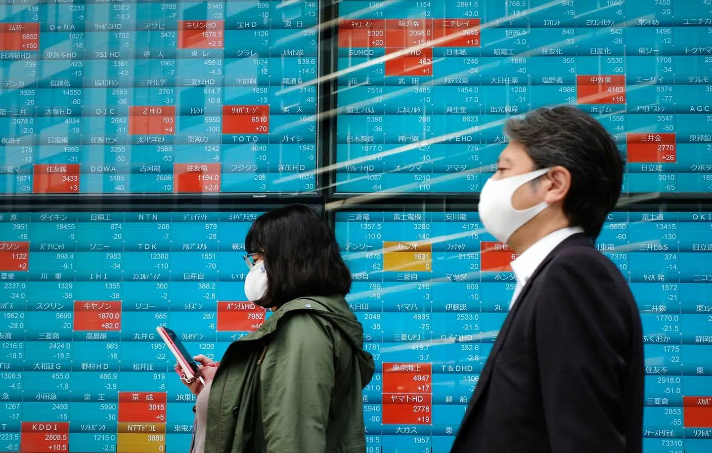 Fodgængere går forbi skilt med aktiekurser fra børsen i Tokyo.