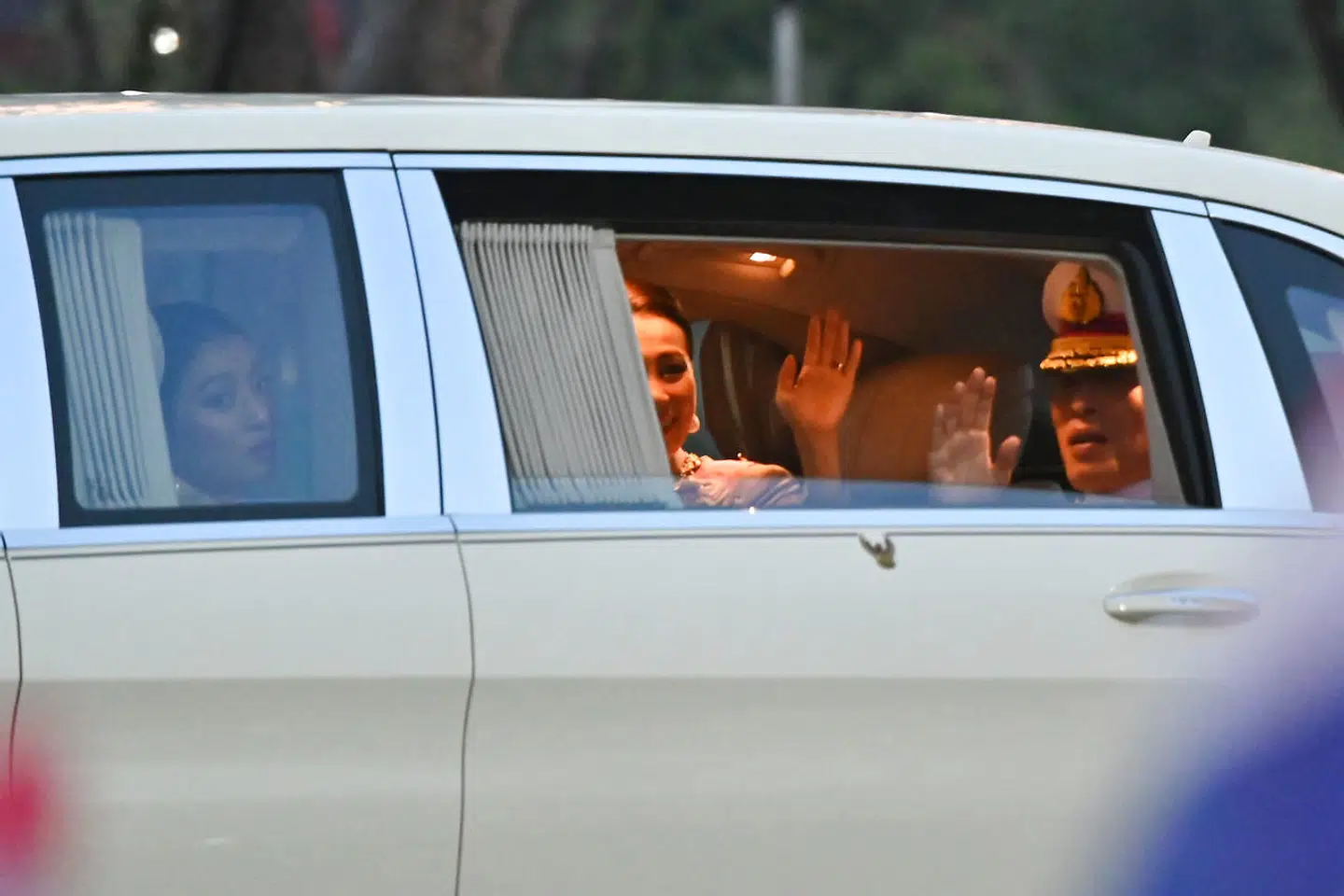 Thailands konge, Maha Vajiralongkorn, dronning Suthida og prinsesse Sirivannavari Nariratana (t.v.) kigger ud af bilen, mens de kører gennem Bangkok 23. oktober.