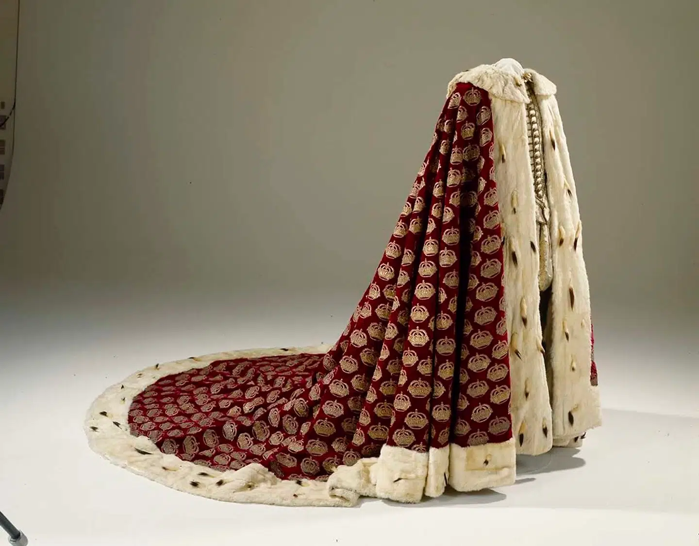 Christian Vs salvingskåbe af rødt silkefløjl, broderet i guldtråd med 1.400 kongekroner og foret med hvidt kaninskind; kanten på oversiden er af hermelin. Christian V bar kåben ved sin kroning i 1671.