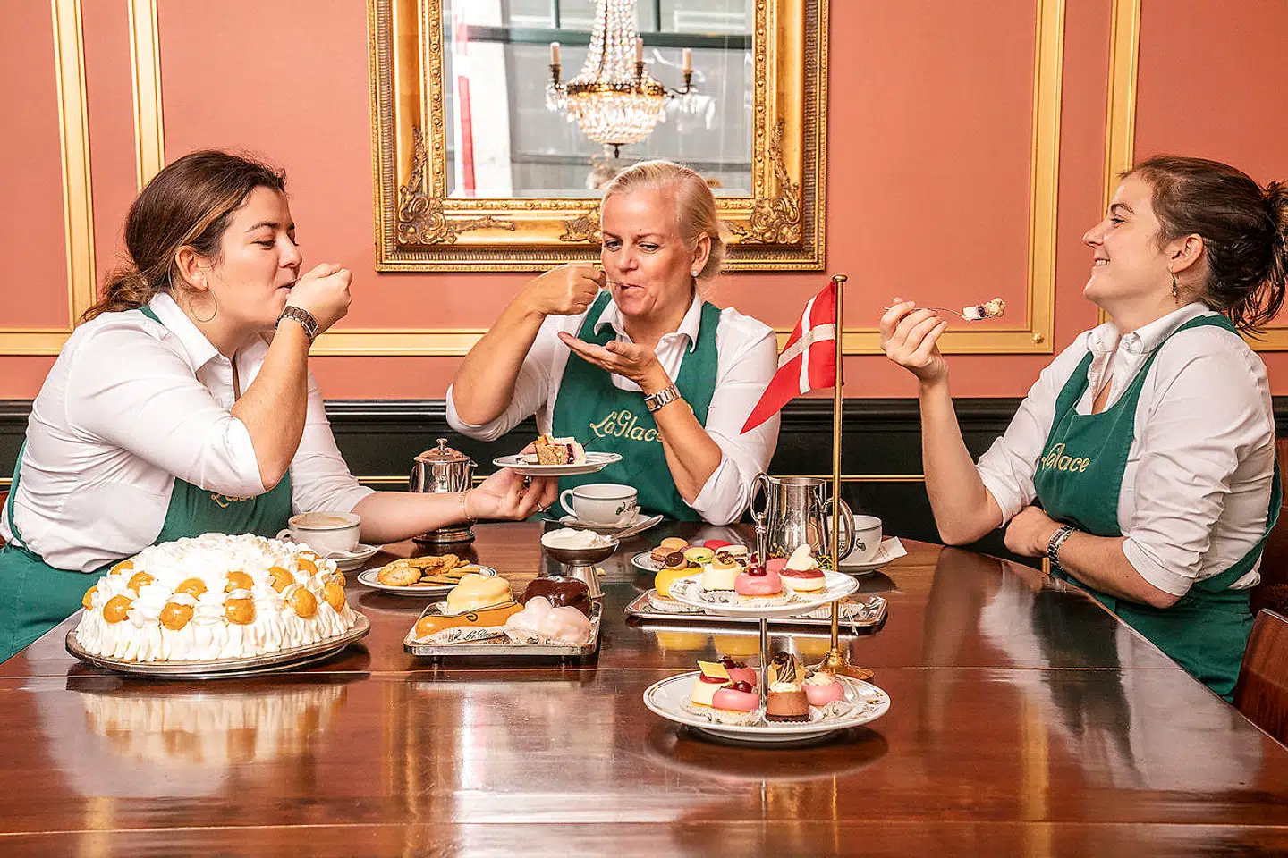 Marianne Stagetorn Kolos med sine to døtre, Maria (tv.) og Laura, der i løbet af de næste fem år skal overtage La Glace. Til venstre ses en af konditoriets klassikere, Sportskagen.