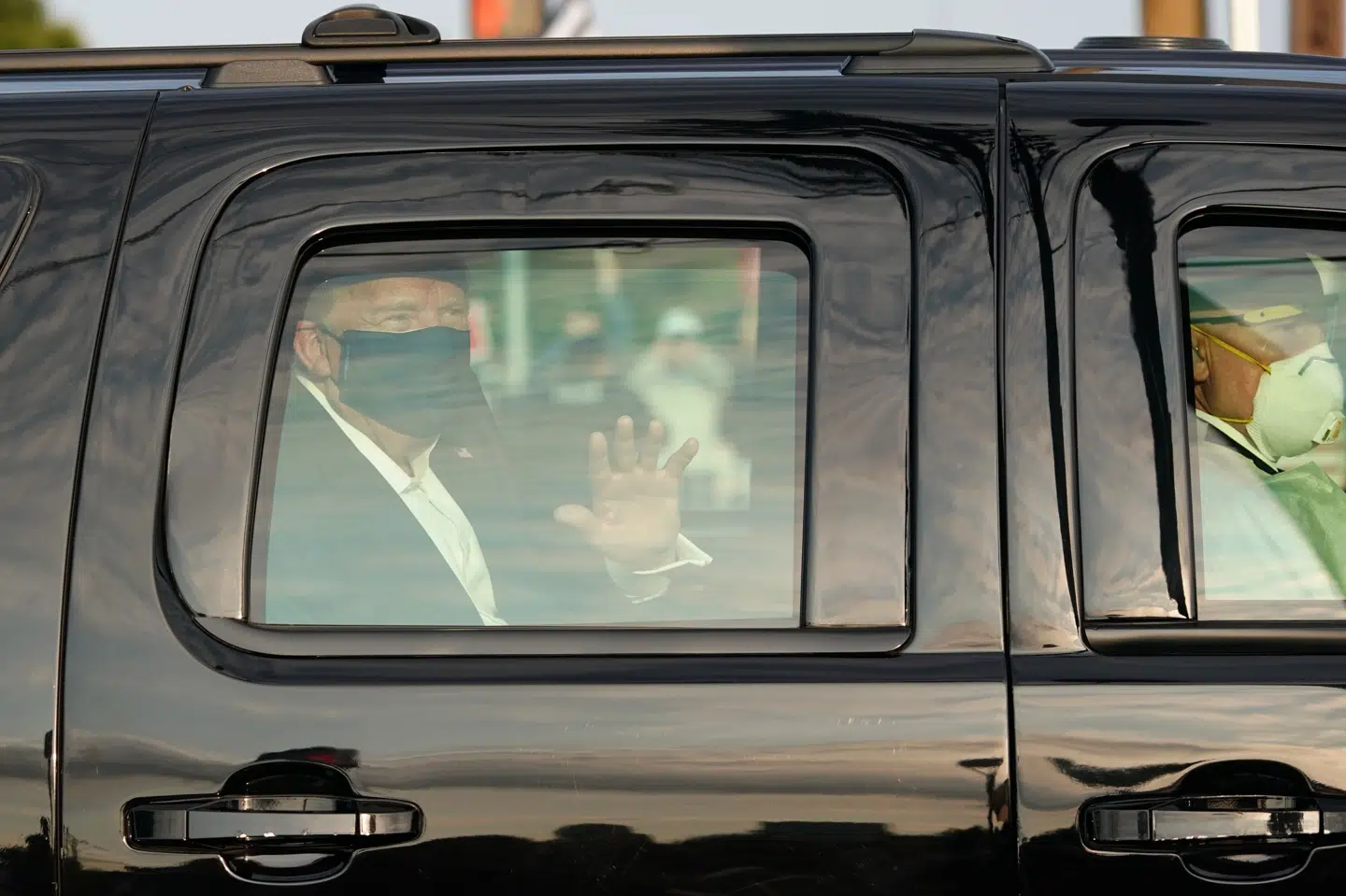 Iført mundbind vinker præsident Donald Trump søndag til sine tilhængere, der er samlet udenfor Walter Reed Medical Center i Bethesda, Maryland. Alex Edelman/Ritzau Scanpix