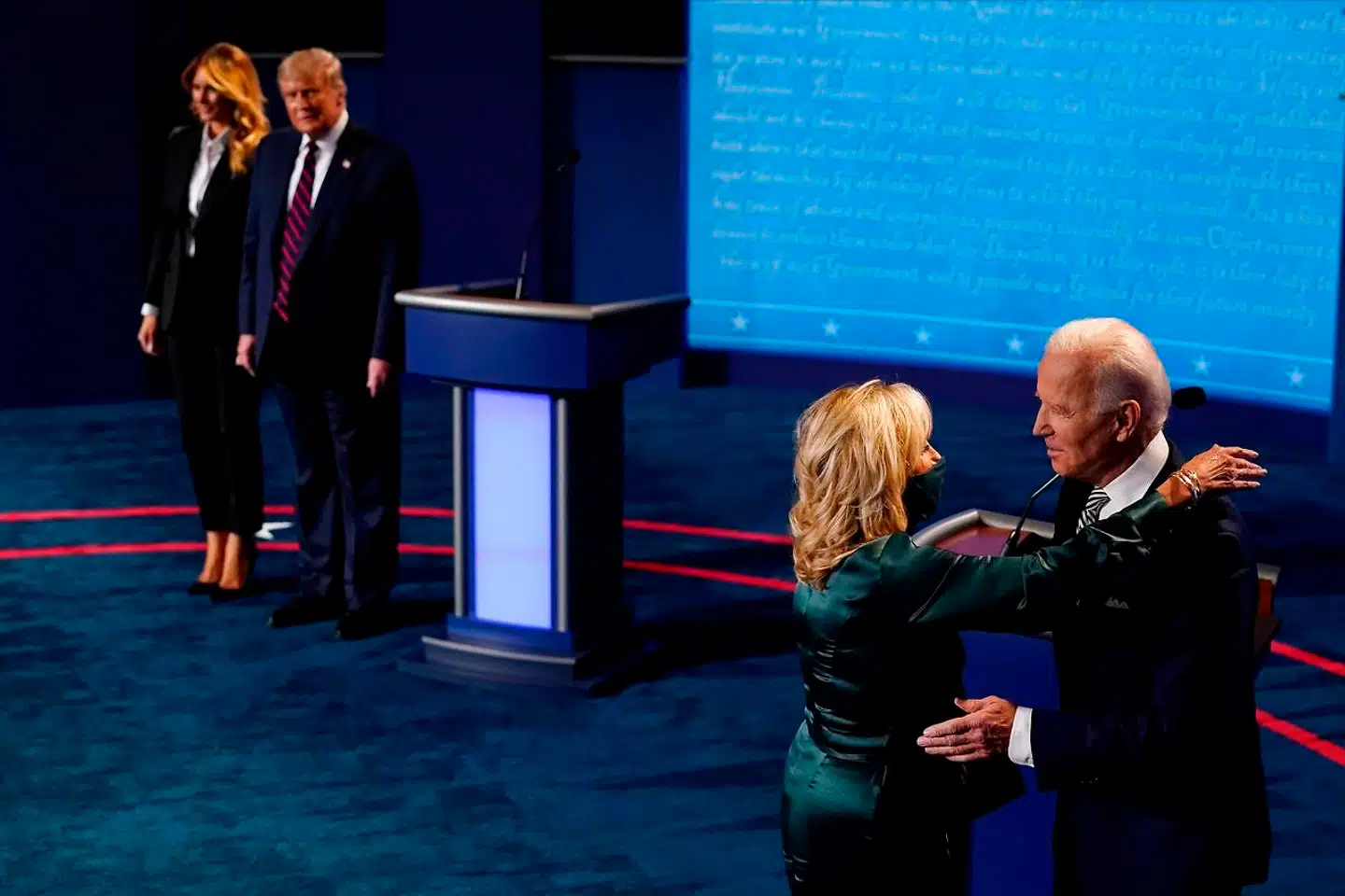 Melania Trump står sammen med præsident Trump, mens den demokratiske kandidat, Joe Biden, omfavner sin kone Jill Biden.