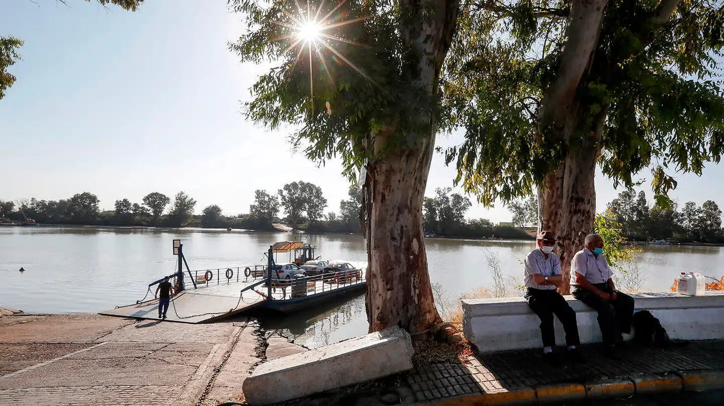 To ældre mænd iført mundbind som beskyttelse mod coronavirus sidder på en bænk Coria del Río - arnested for en anden epidemi, der i ligeledes især truer deres aldersgruppe.